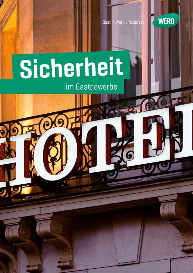 Grünes Schild mit Schriftzug „Sicherheit im Gastgewerbe“ an einem Balkon mit Ziergeländer und beleuchtetem Fenster