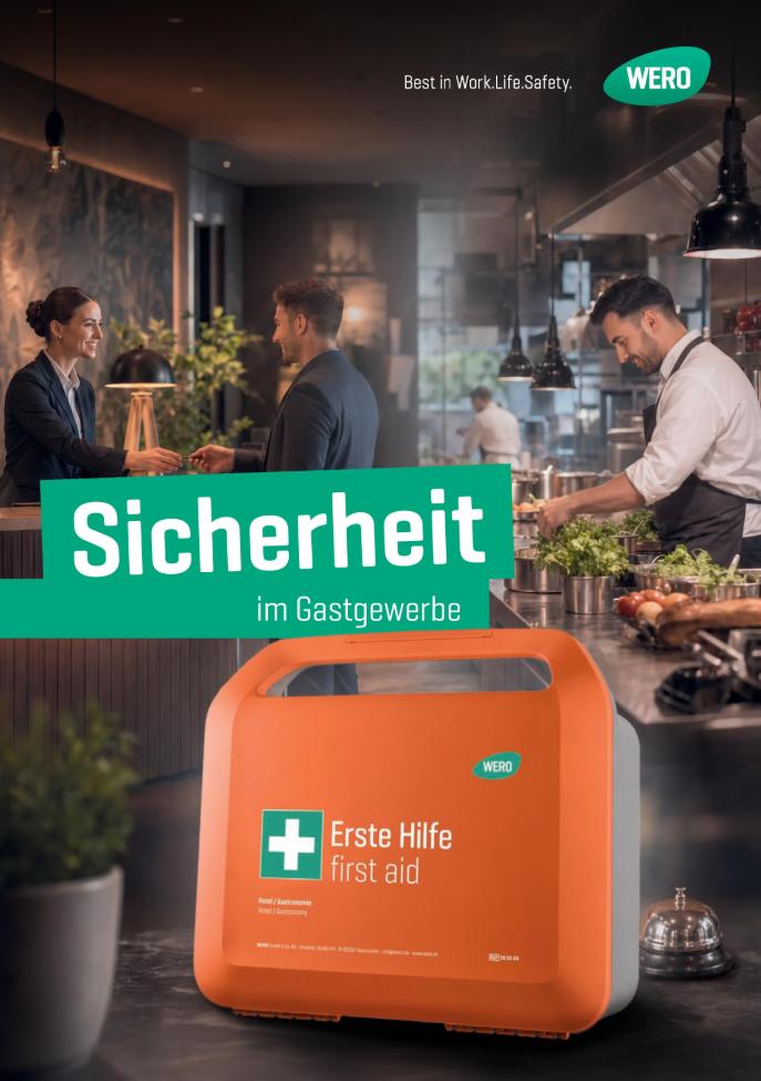 Orange Erste-Hilfe-Box mit weißem Kreuz, Aufschrift „Erste Hilfe first aid“, in einer Küche auf dunkler Arbeitsfläche.