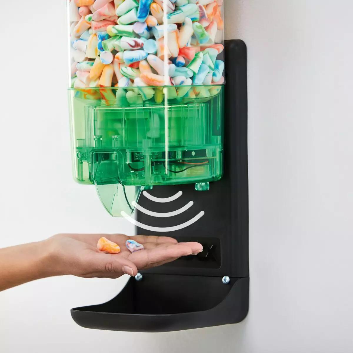 Hand hält bunte Gehörschutzstöpsel, die aus dem MOLDEX TouchFree Spendermechanismus berührungslos und hygienisch entnommen werden.