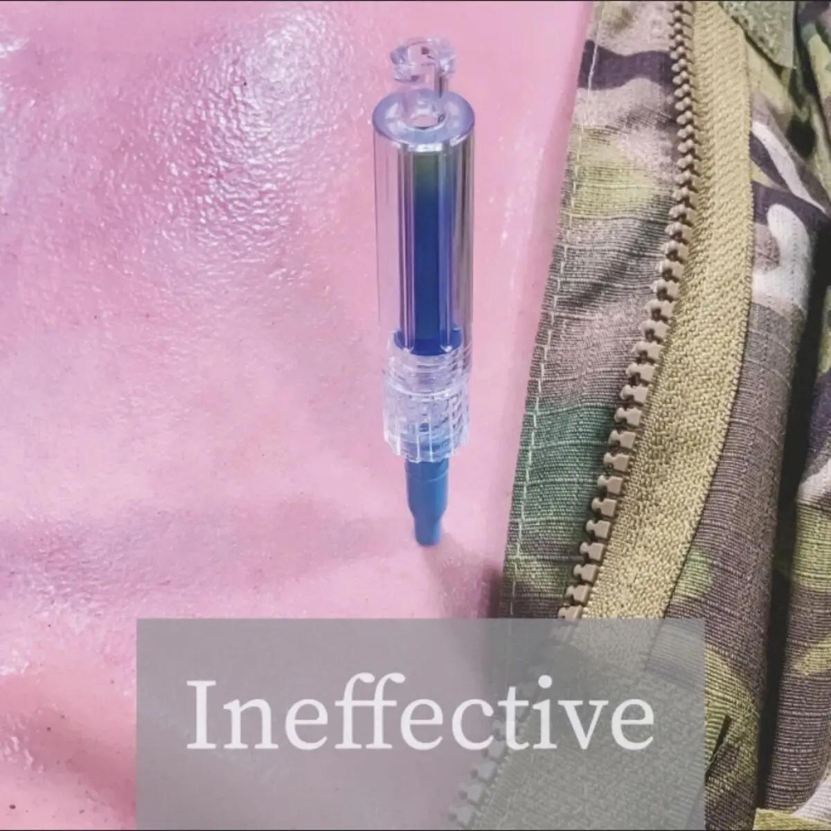 Eine Capnospot® Pneumothorax Dekompressionsindikator Spritze mit blauer Kammer wird in rosa Haut gestochen, daneben ein Tarnjackenärmel sichtbar.
