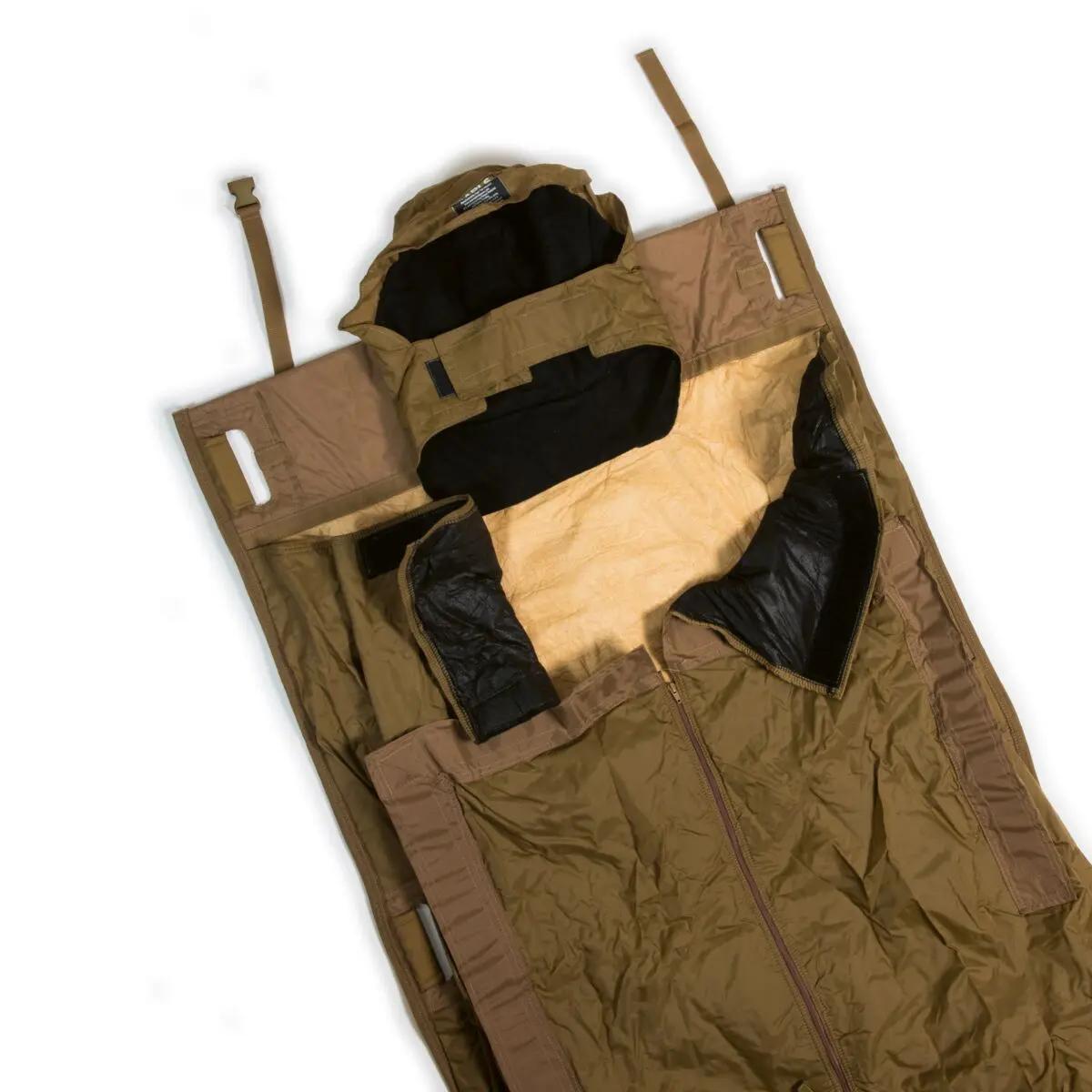 Ein geöffneter APLS Thermal Guard Schlafsack zeigt wasserabweisendes, beiges Material, schwarzen Innenfutter und mehrere Trage- sowie Befestigungsriemen.