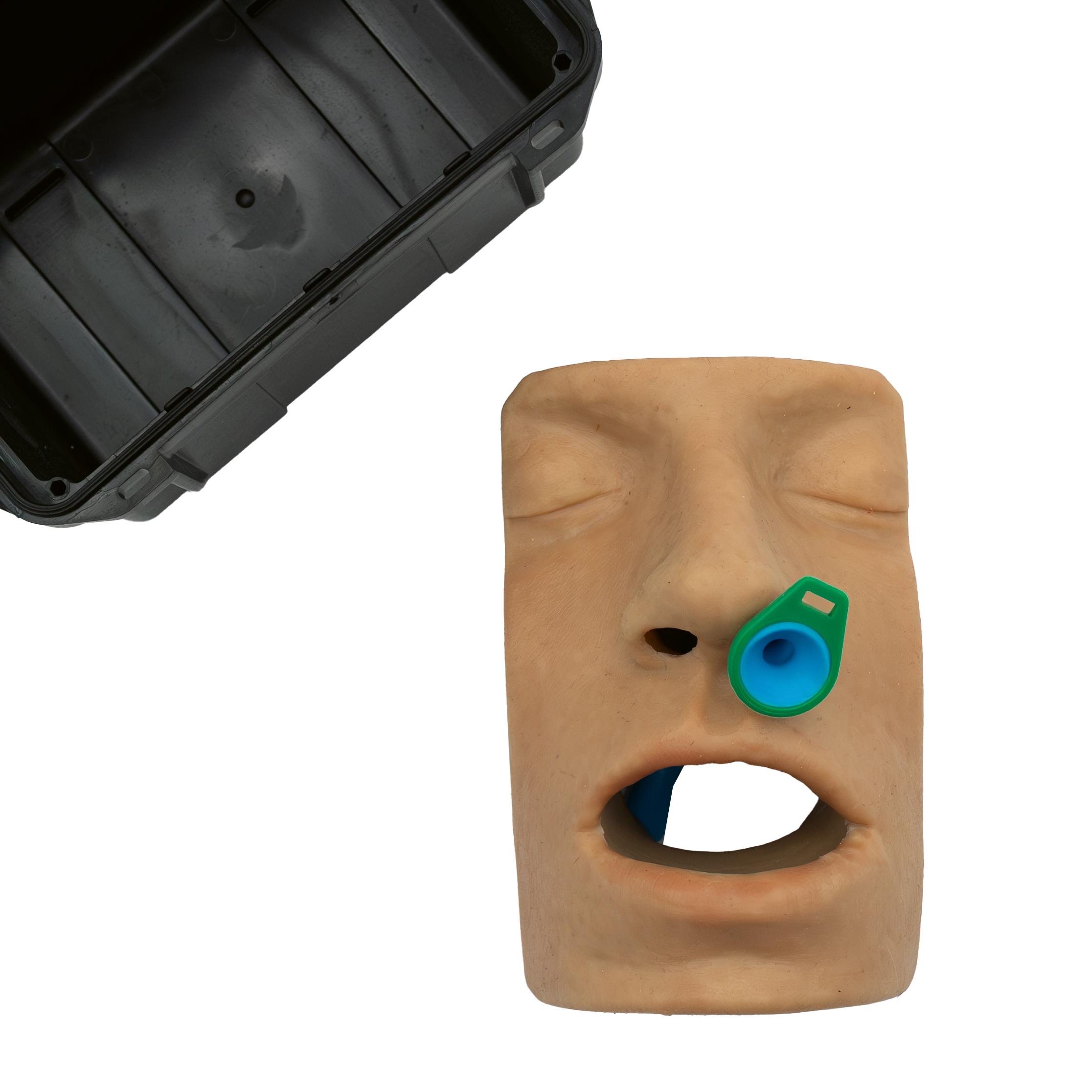 Beiger Techline Nasopharyngeal-/Wendl-Tubus-Trainer mit stilisiertem Gesicht, grün-blauem Auge und rechteckiger Mundöffnung, daneben schwarzer Behälter.