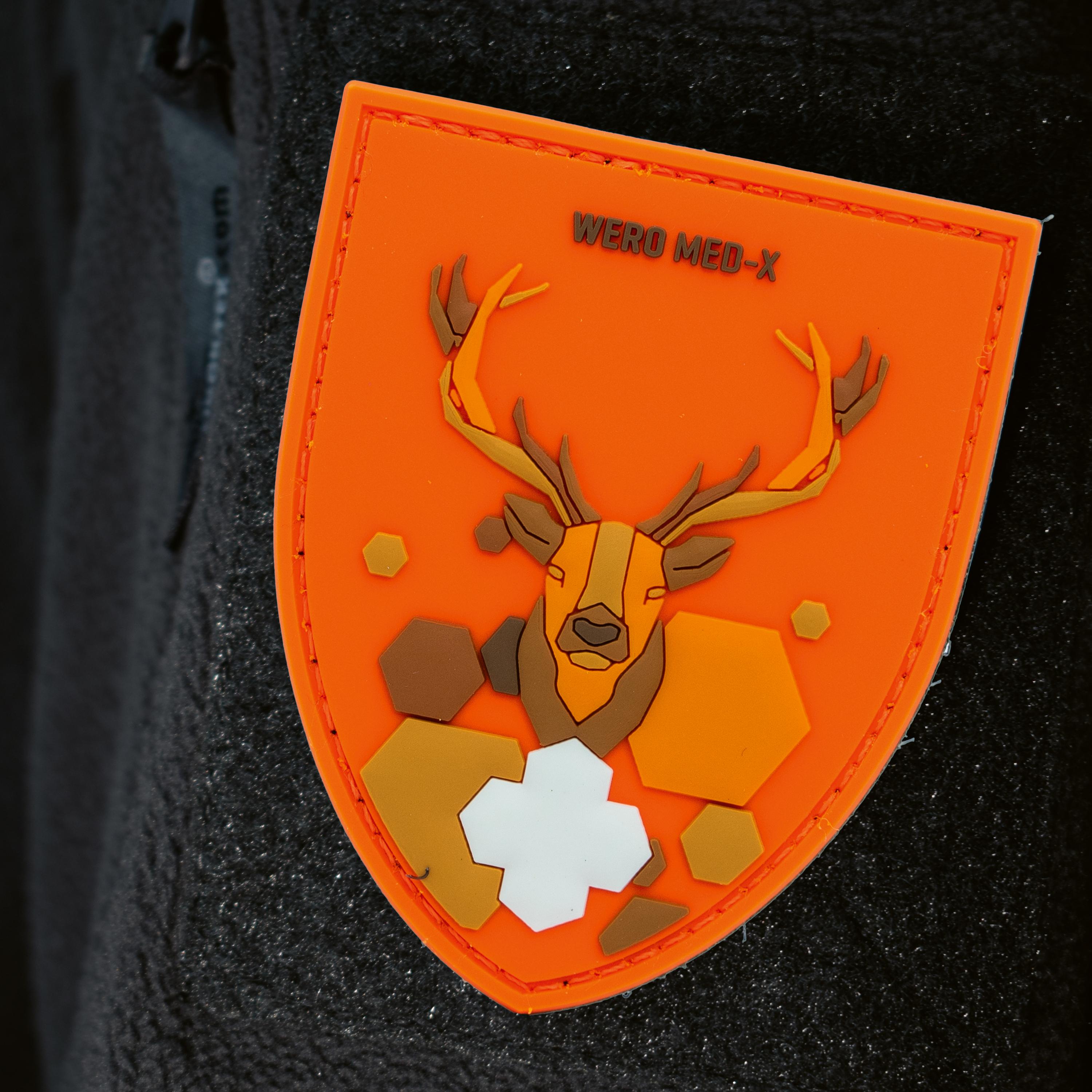 Patch WERO MED-X® Hunter Medic Pack als orangefarbener Schild mit Hirschkopf, schwarzen „WERO MED-X“ Schriftzug und weißem Kreuz am Jackenärmel.
