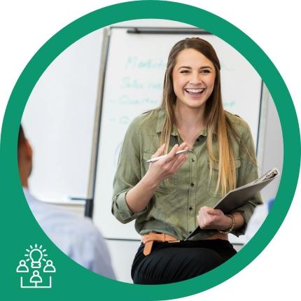 Junge Frau mit Klemmbrett lächelt bei Präsentation vor Whiteboard mit Aufschrift zu Marktforschung.