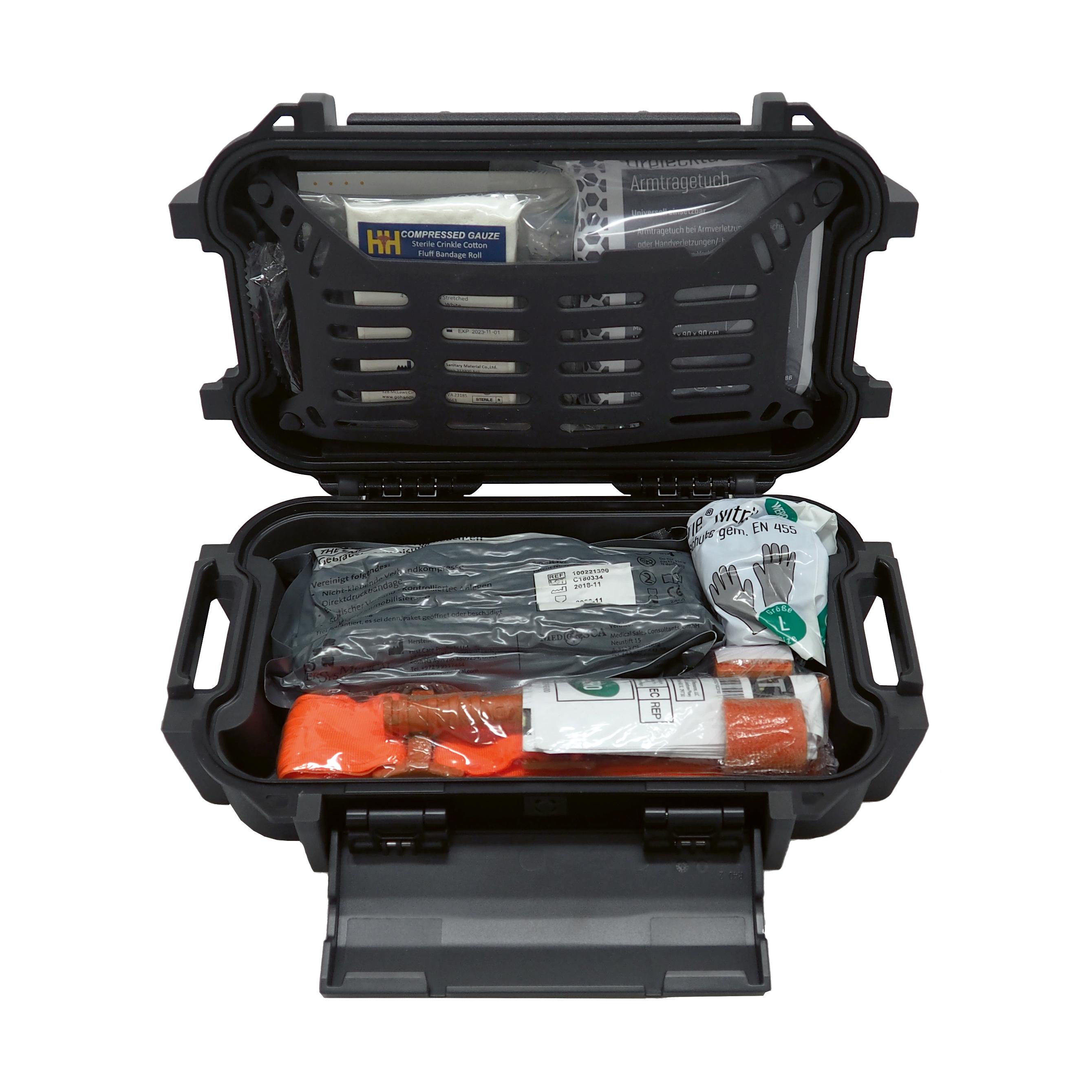 Ein geöffnetes WERO MED-X® eXtrem Outdoor First Aid Kit mit verschiedenen Verbandsmaterialien, orangefarbenem Tourniquet und blauen Einmalhandschuhen.