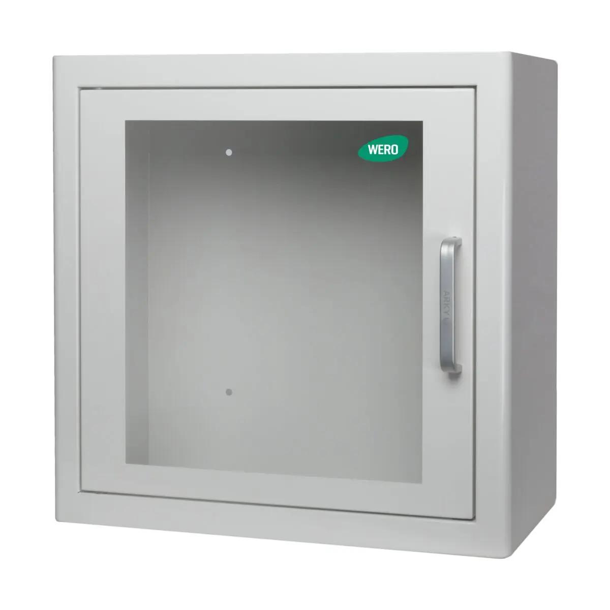 Geschlossener WERO AED-Wandschrank aus weißem Metall mit klarer Glastür, stabilem Griff und grünem WERO-Aufkleber auf der Front.