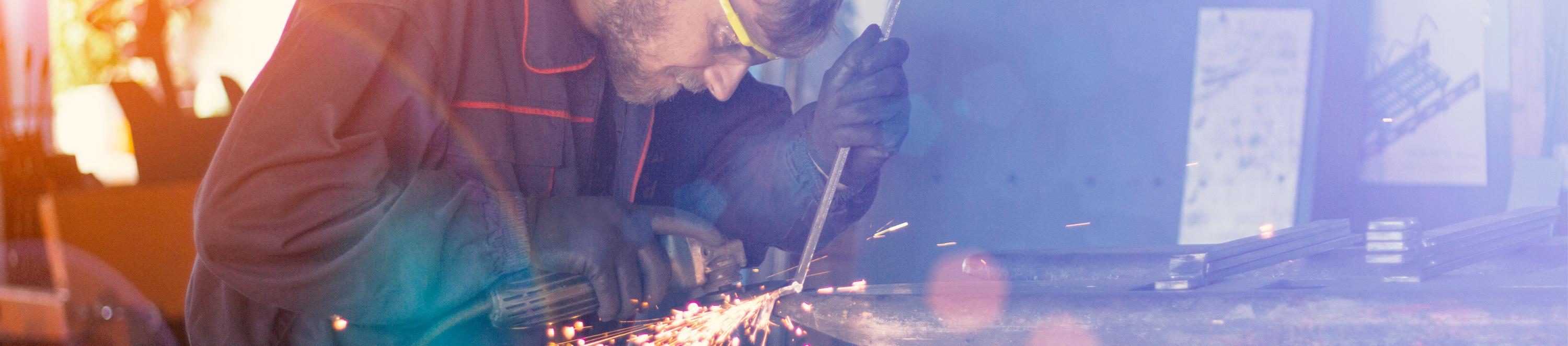 Eine Person flext an einem Stück Metall. Funken sprühen.