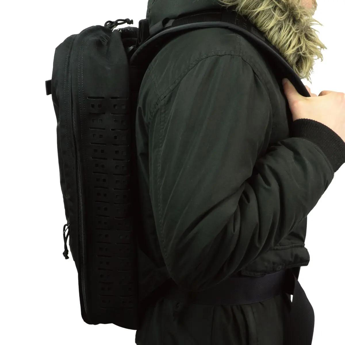 Eine Person trägt den schwarzen PARAMEDYK® Notfallrucksack mit ergonomischem Design, top Handle und abnehmbarem Schultergurt, seitlich strukturiert und kleinem Reißverschluss.