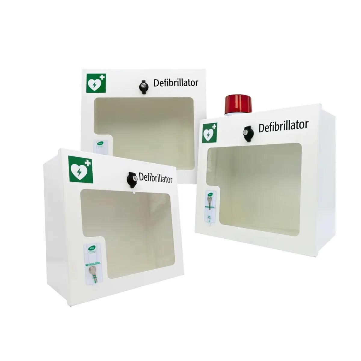 Drei AED-Wandschränke (gebraucht) - mit Alarmfunktion (Sirene), aus Stahlblech, mit Sichtfenster, Licht und grünem Defibrillator-Herz, werden gezeigt.