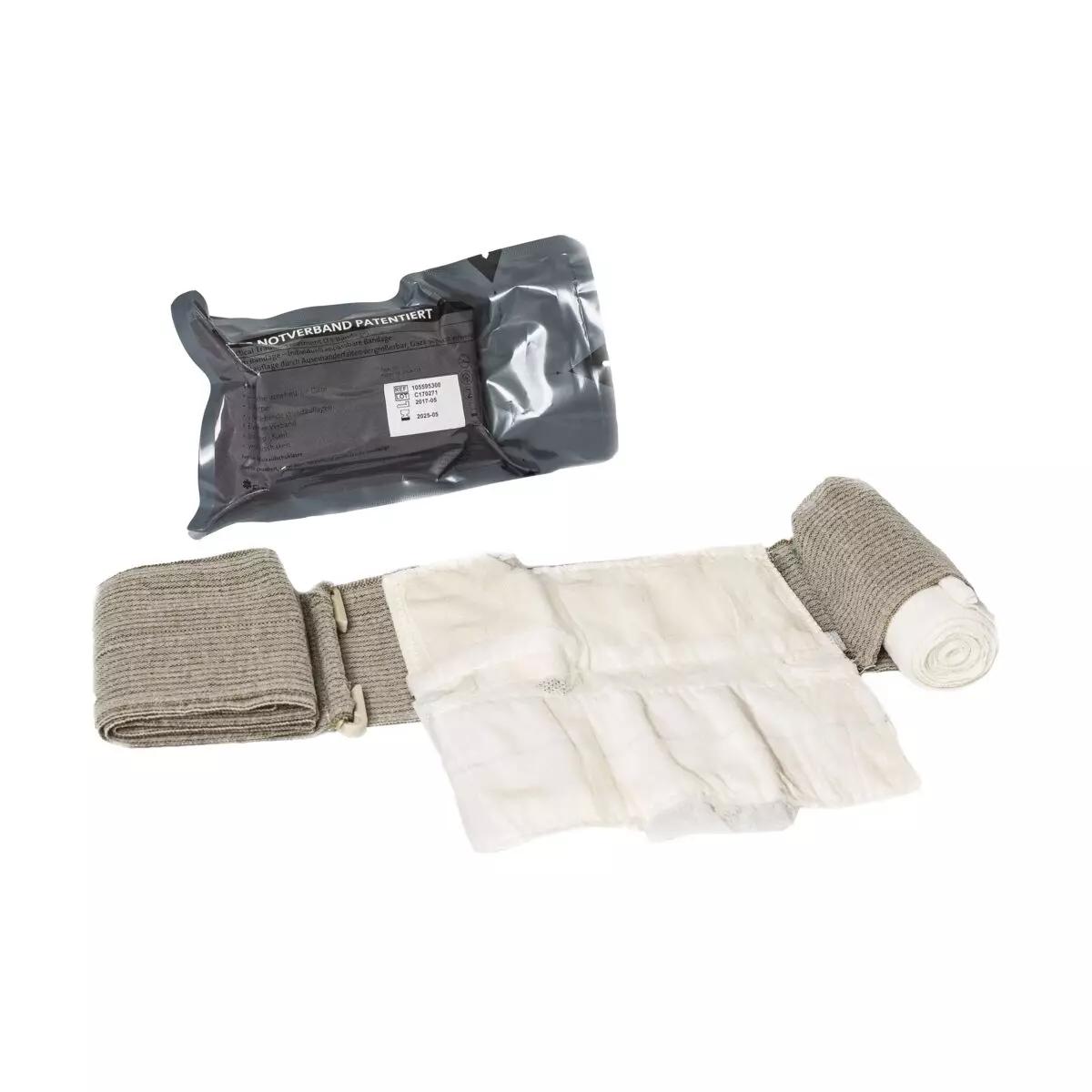 Ein schwarzes T3 Bandage™ Notfallpaket liegt neben einer aufgerollten, beigefarbenen Bandage mit zwei Wundauflagen und grauen Befestigungsriemen.