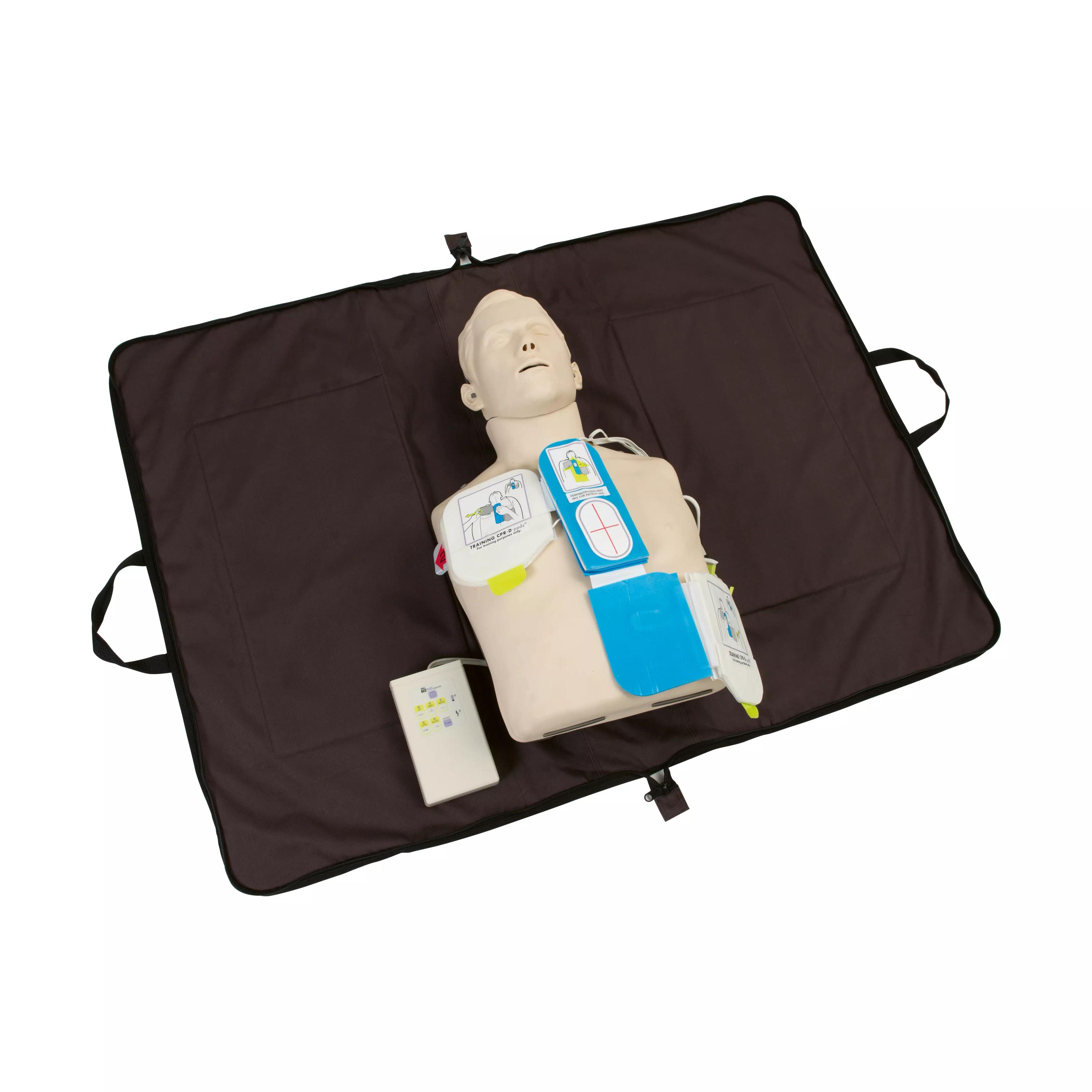 Herz-Kreislauf-Trainingspuppe mit blauem Gurt, gelbem Defibrillator und weißem Gerät, liegend in schwarzer Tragetasche.