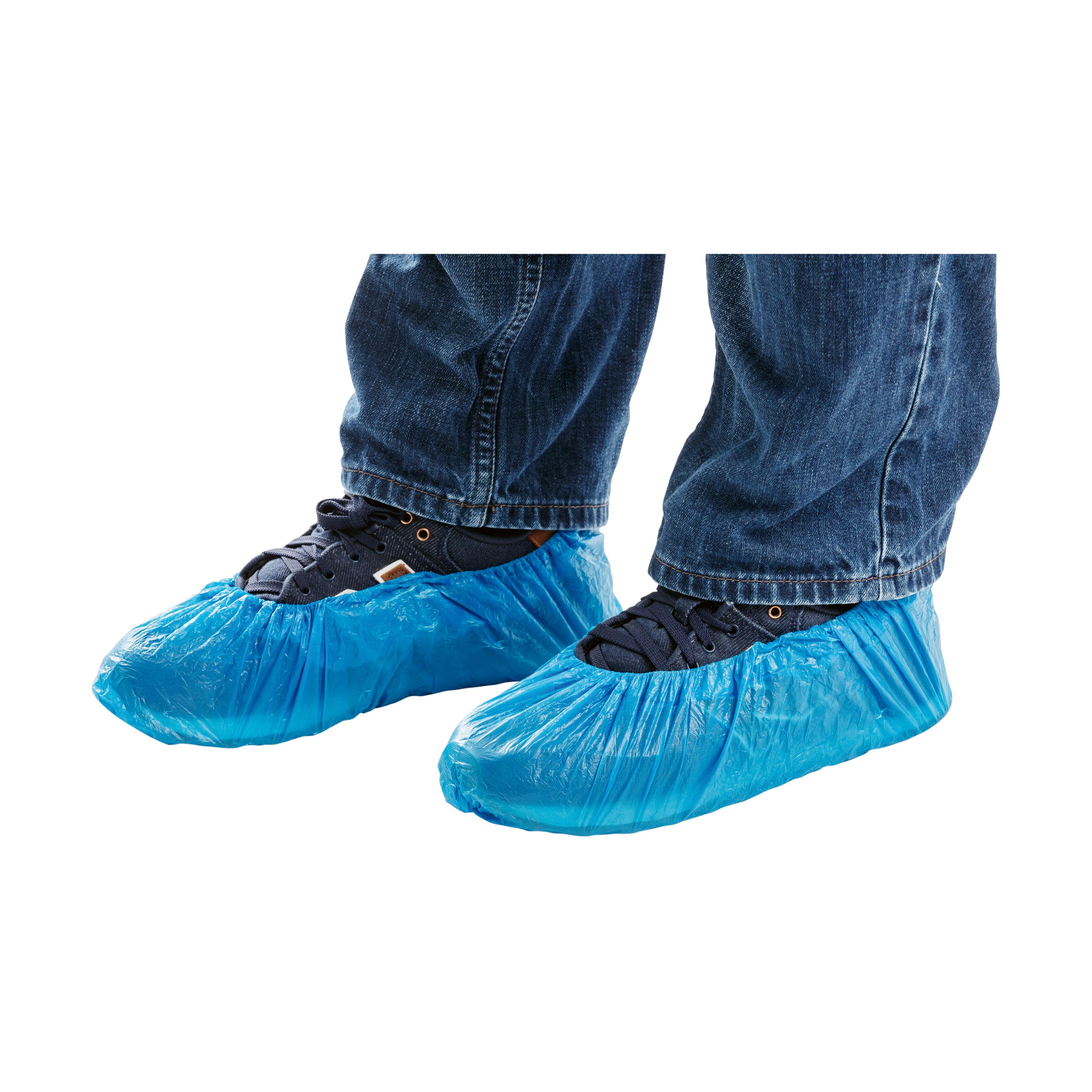 Eine Person trägt Überschuhe mit Gummizug aus blauem, gehämmertem Polyethylen über Sneakern und Jeans, die Schuhkappen sind leicht gerafft.