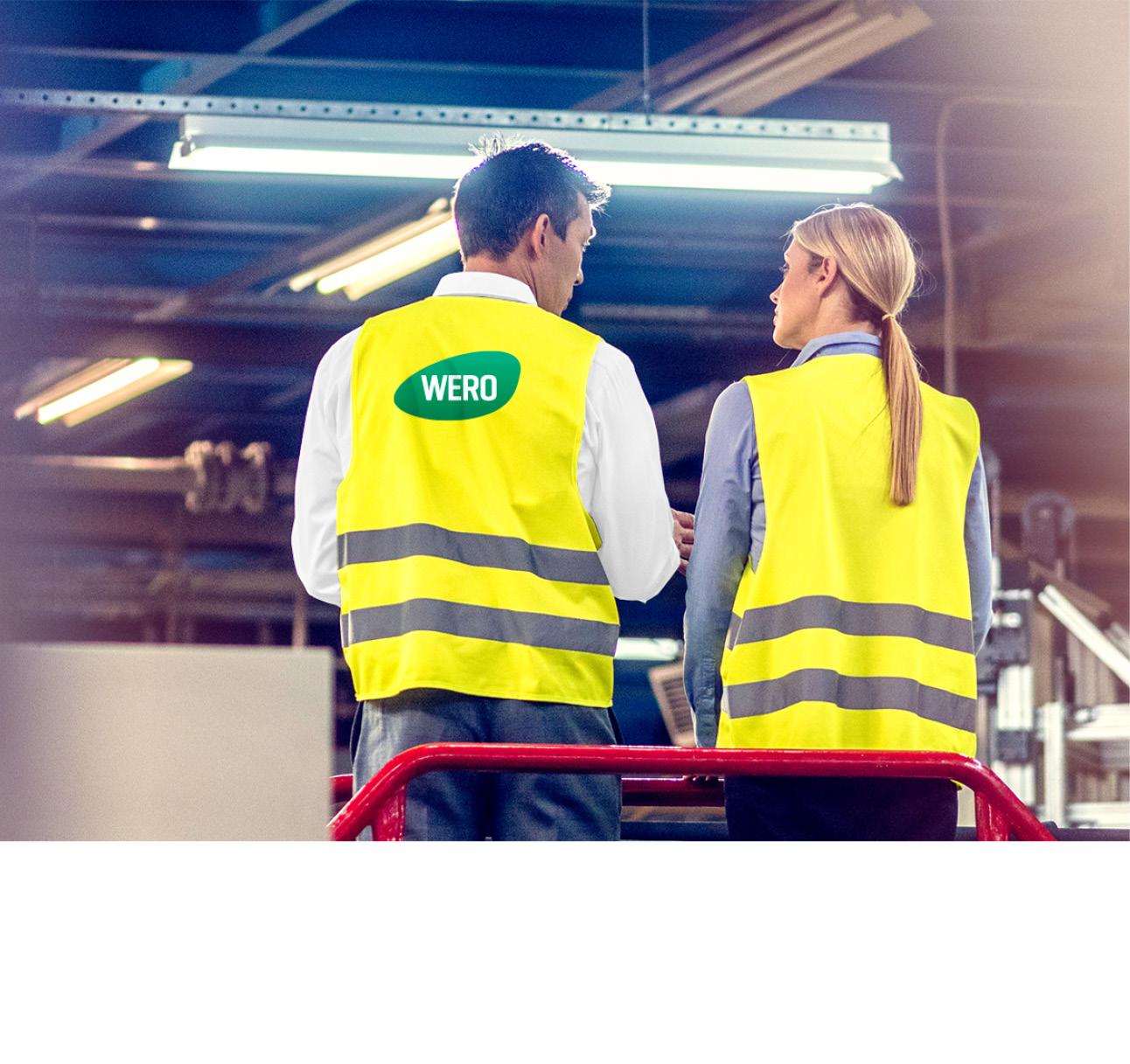 Zwei WERO Mitarbeitende stehen mit dem Rücken zur Kamera. Sie tragen neongelbe Warnwesten