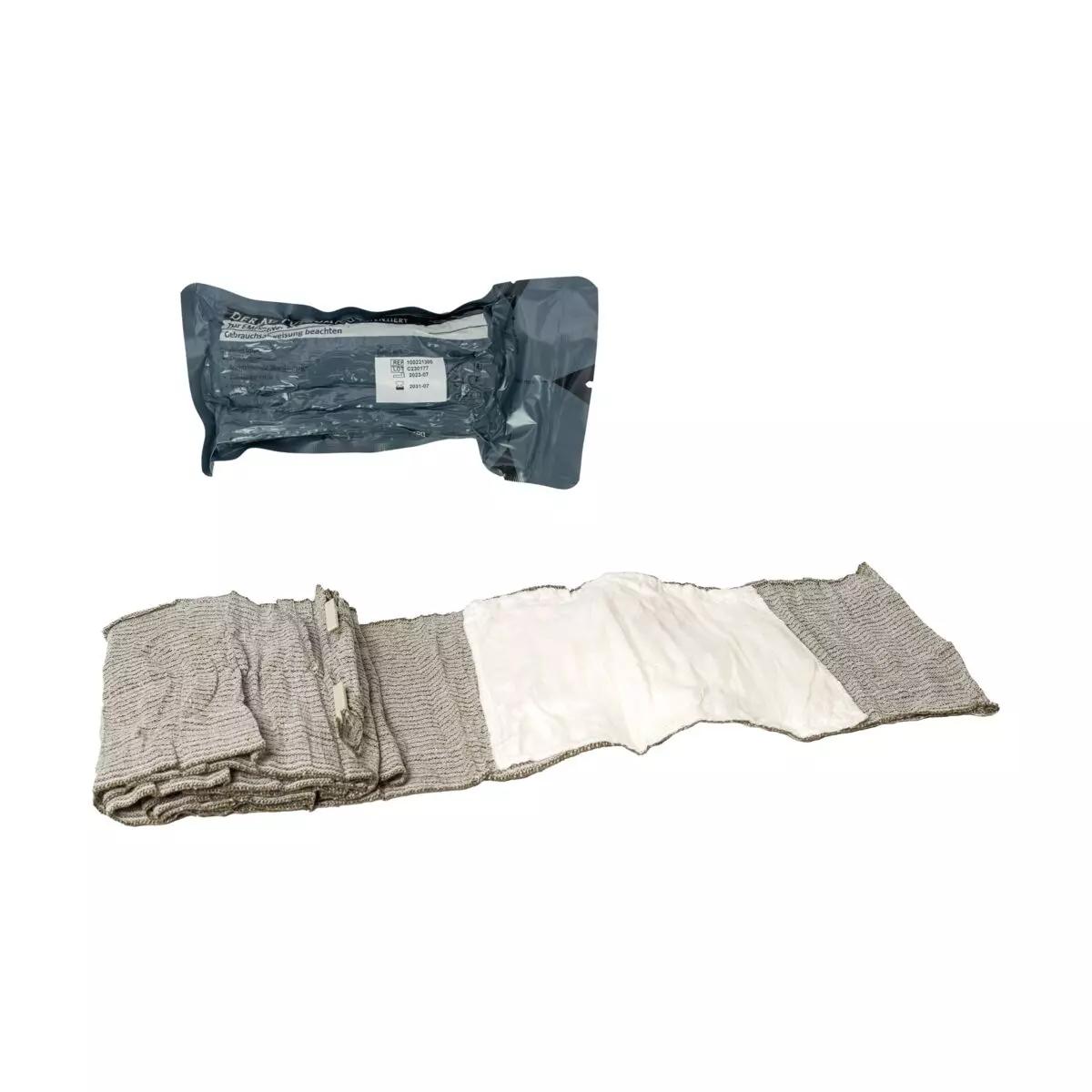 Die Emergency Bandage®, das Original - Oliv, 15 cm als aufgewickelte, texturierte Notfallbandage in steriler Verpackung mit sichtbarem Markennamen.