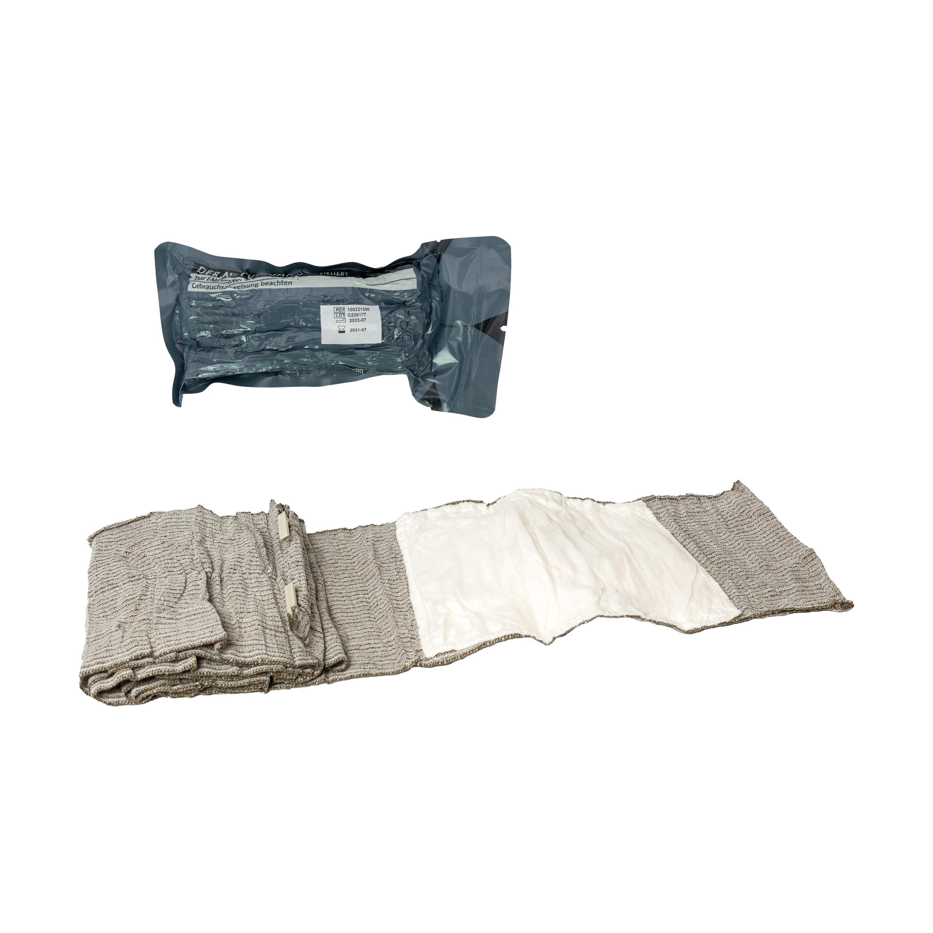 Die Emergency Bandage®, das Original - Oliv, 15 cm als aufgewickelte, texturierte Notfallbandage in steriler Verpackung mit sichtbarem Markennamen.