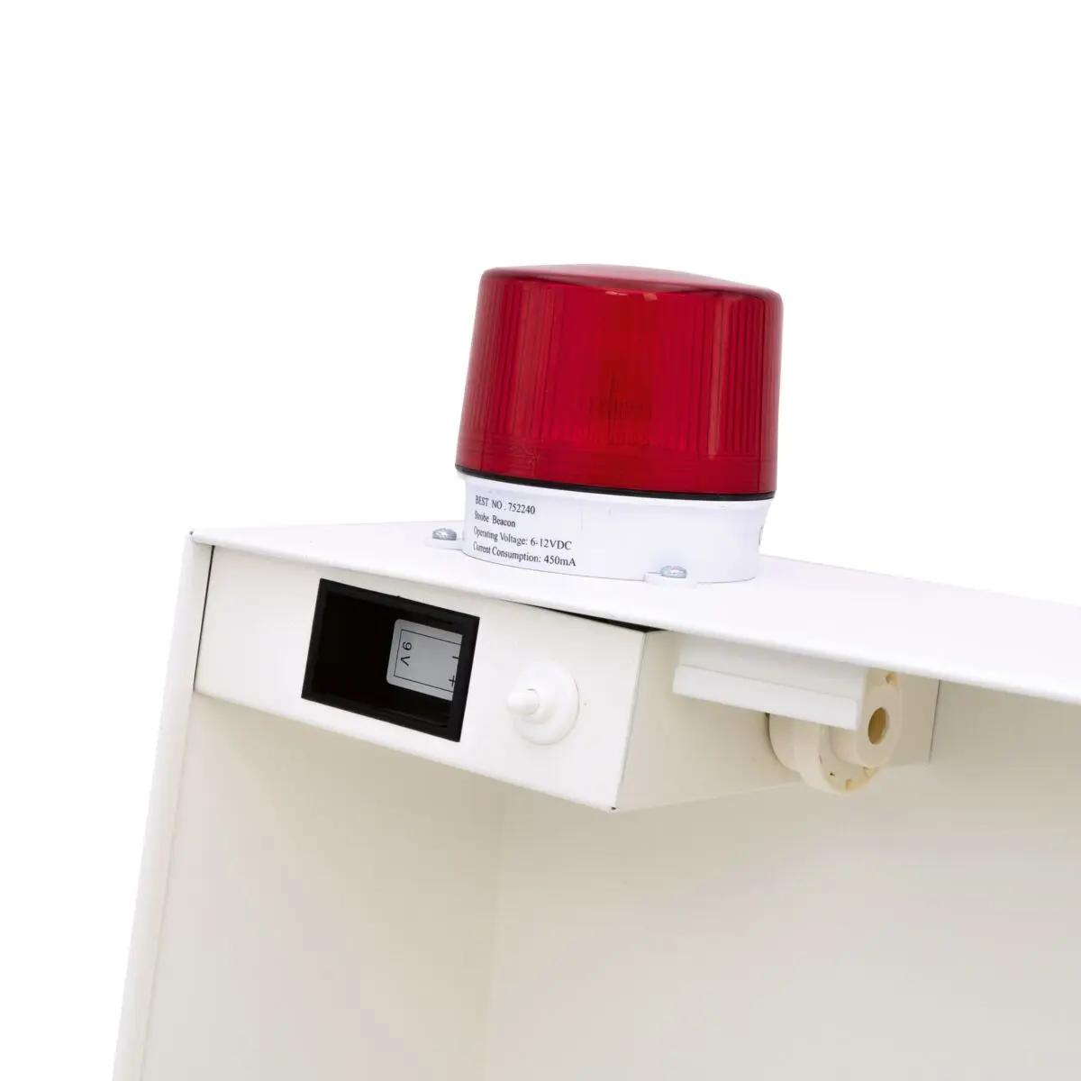 Warnleuchte mit Sirene und Leuchte auf einem AED-Wandschrank (gebraucht) aus Stahlblech mit Display und Bedienelementen auf weißer Oberfläche.