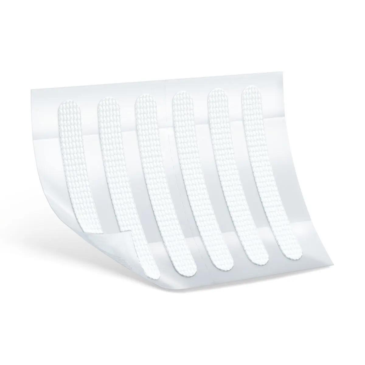 Ein Leukoplast® Wundnahtstreifen - Größe XS klebt auf einer weißen Fläche, zeigt sechs parallel verlaufende, gebogene Streifen mit flexibler, leicht strukturierter Oberfläche.