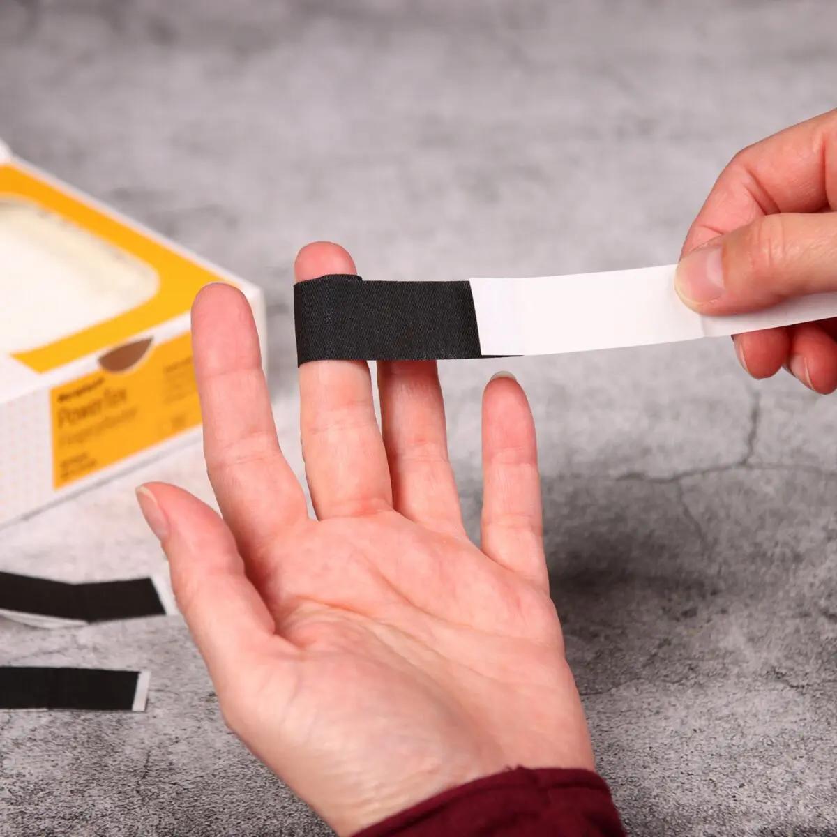 Ein Finger wird mit Fingerpflaster Weroplast® PowerTex umwickelt, das durch verstärkte Klebkraft und schwarzes Gewebe besonders robust ist.