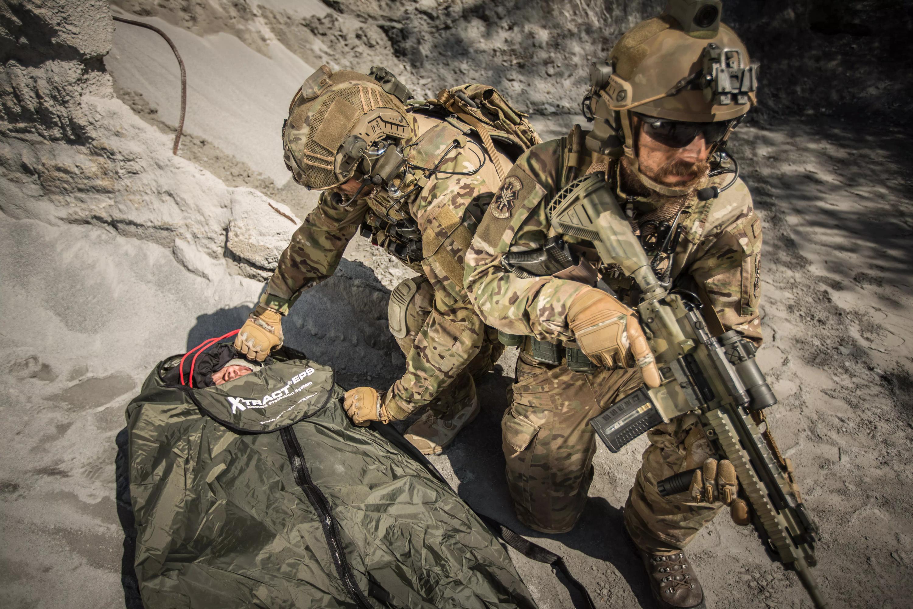 Ein Soldat verwendet das Xtract™ SR Element Protection System (EPS), das eine verletzte Person auf einem dunklen, aufblasbaren Schutzsack vor Unterkühlung bewahrt.