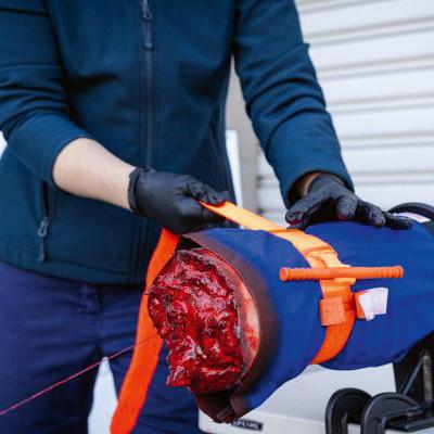 Eine Person hält den TRAUMASIM® Emergency Tourniquet Trainer mit blutendem Wundmodell, realistischen Geweben und trainingsoptimiertem Zylinder.