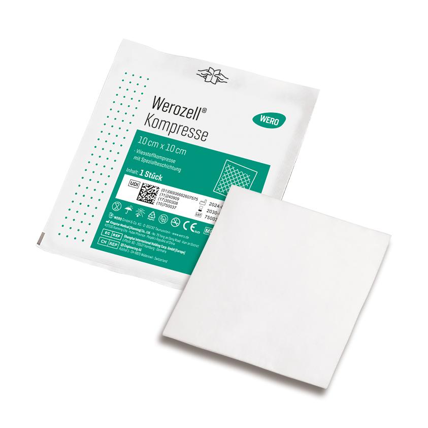 Sterile Werozell® Kompresse, 10 x 10 cm, aus weißem Vlies mit spezieller Beschichtung, teils aus der Verpackung gezogen, grün etikettiert.
