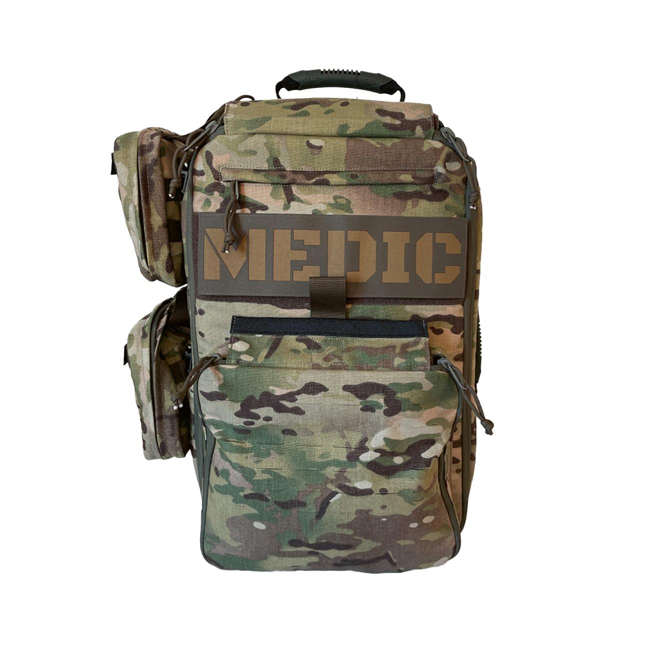 Tarnmuster Medizinische Tasche mit schwarzem Tragegriff, braunem MEDIC-Aufdruck und mehreren Fächern sowie Reißverschlüssen.