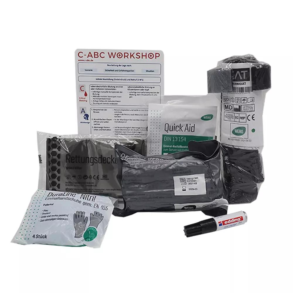Das C-ABC Adventure First Aid Pack mit Notfallbeatmungshilfe, Notfallprodukten und Edding liegt samt Handschuhen, Verbänden und Zubehör geordnet bereit.