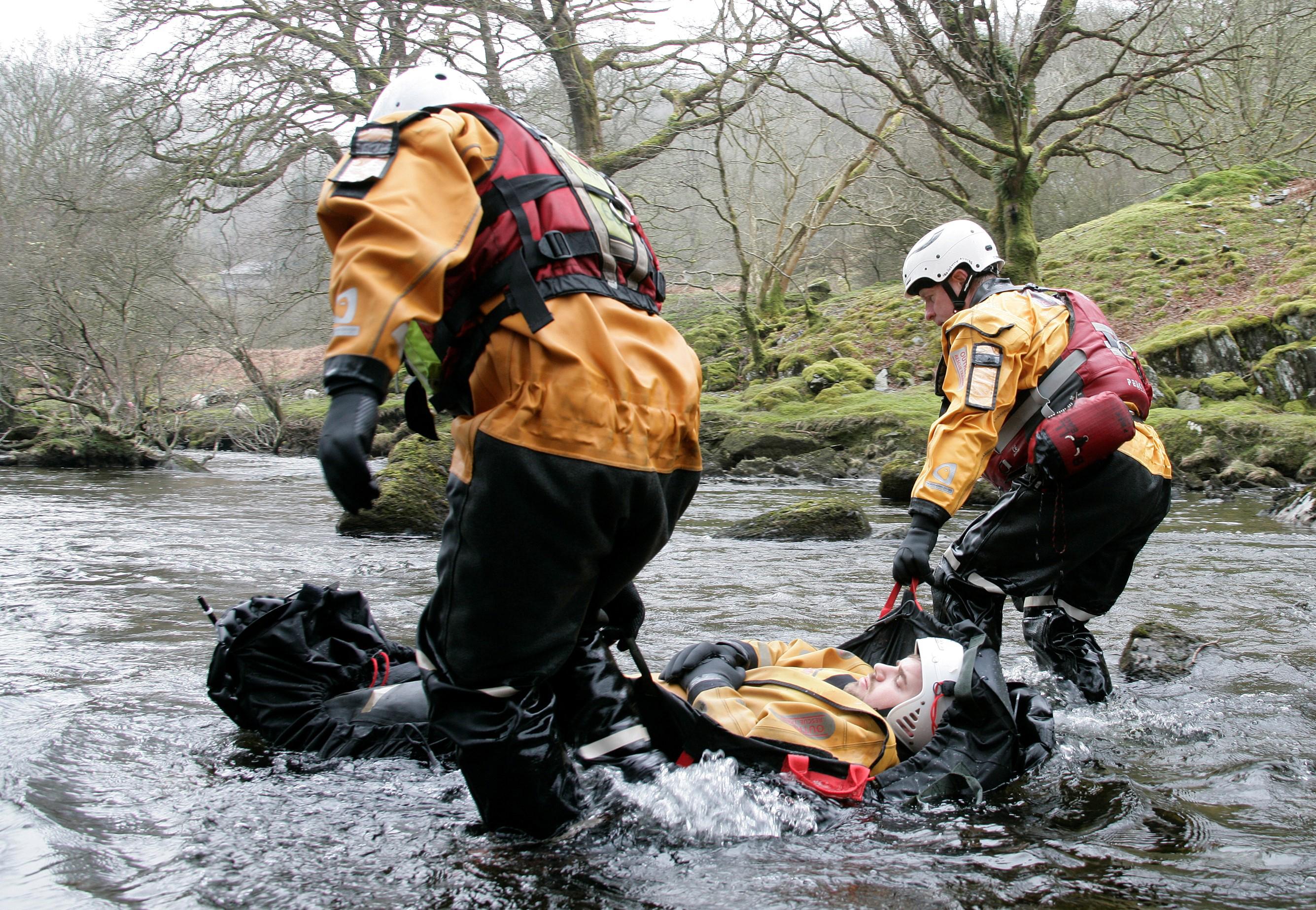 Eine Person liegt auf einem Xtract™SR Afloat, das dank seitlicher und kopfseitiger Luftkissen von Einsatzkräften im Wasser stabil geführt wird.