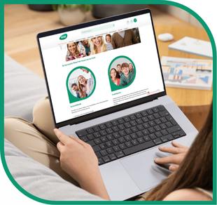 Eine Person nutzt ein silbernes Laptop, auf dessen Bildschirm eine Stammbaum-Website mit Fotos von Familien zu sehen ist.