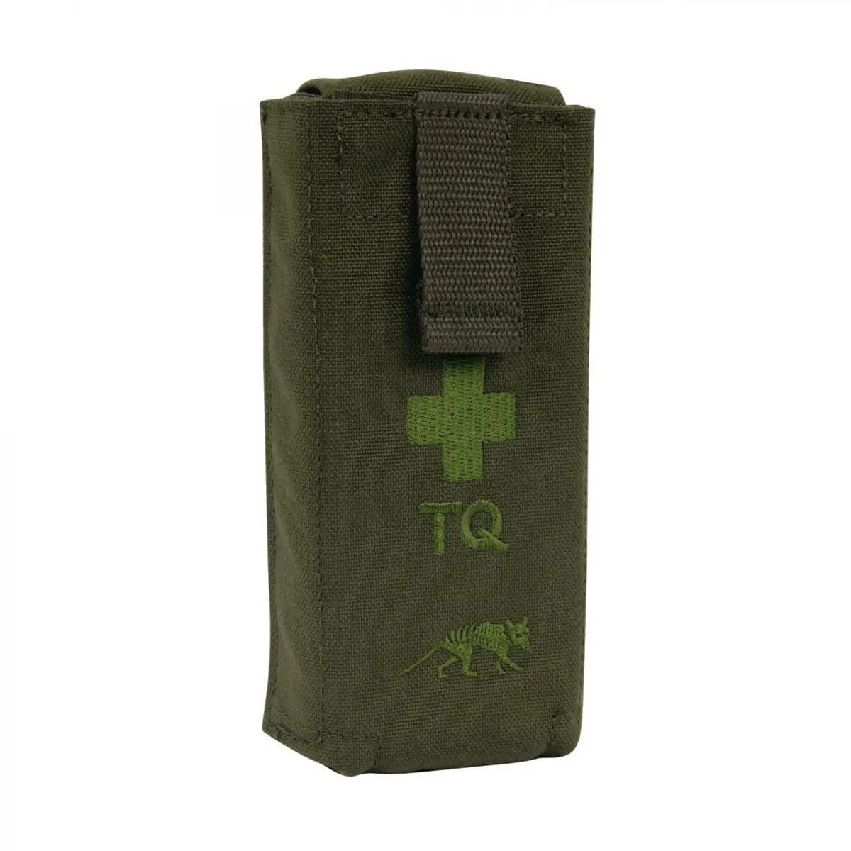 Olivgrüne TT Tourniquet Pouch II steht aufrecht, zeigt grünes Kreuz und TQ-Schriftzug auf Vorderseite, oben mit dunkel verstellbarem Trageriemen.