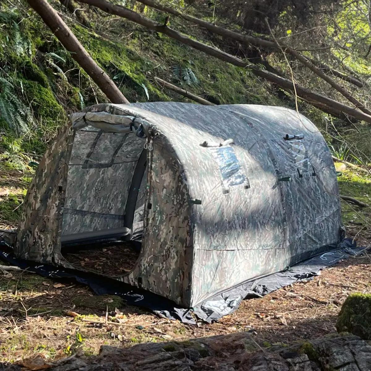 Taktisches Rettungszelt RIGLOO Defender - Grün als aufblasbares Camouflage-Zelt mit abnehmbarem Boden und sechs Fenstern im Wald aufgebaut.