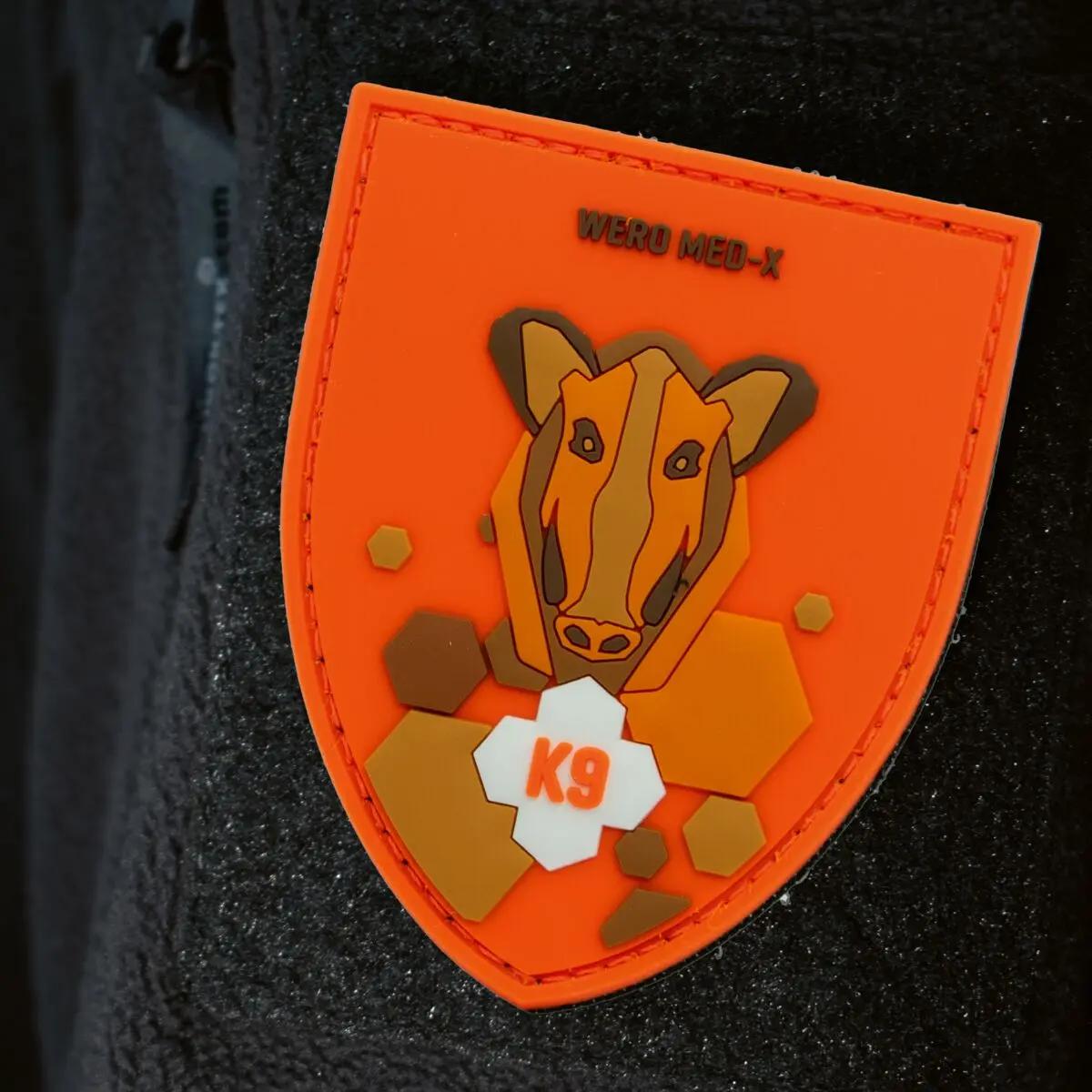 Patch WERO MED-X® K9 Hunter Medic Pack in Schildform zeigt ein stilisiertes Wildschwein, rote Nähte, weißen Hexagon mit Zahl 9 und Aufschrift WERO MED-X.