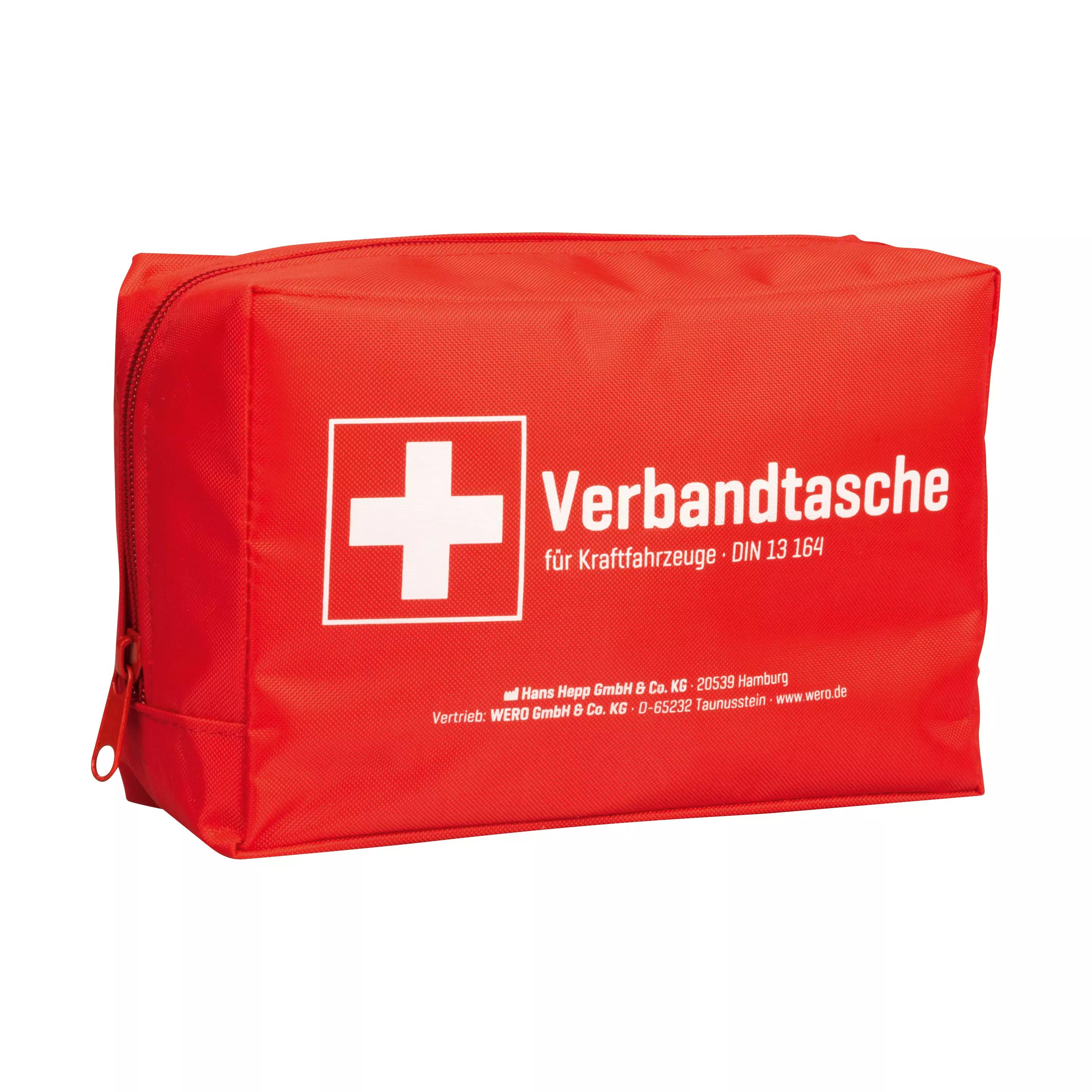 Eine rote Verbandtasche Auto (KFZ) DIN 13164:2022-02 aus robustem Nylon mit weißem Kreuz, Reißverschluss und deutlicher Beschriftung steht aufrecht.