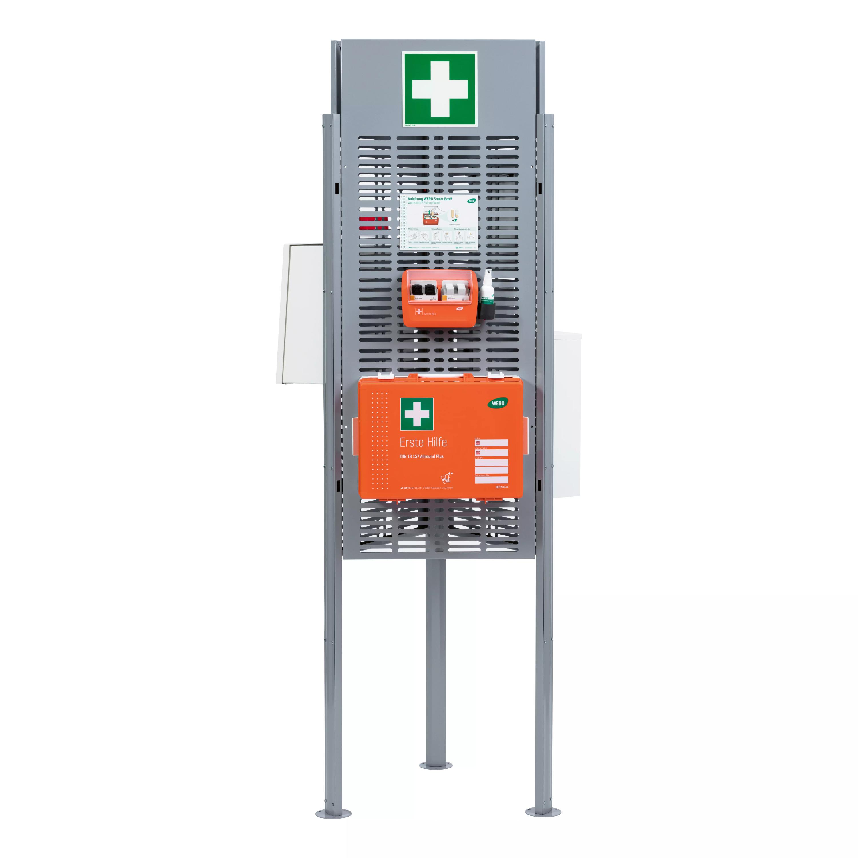 Graue Notfallstation mit grünem Kreuz und orangefarbenem Erste-Hilfe-Kasten zur Bereitstellung medizinischer Hilfe.