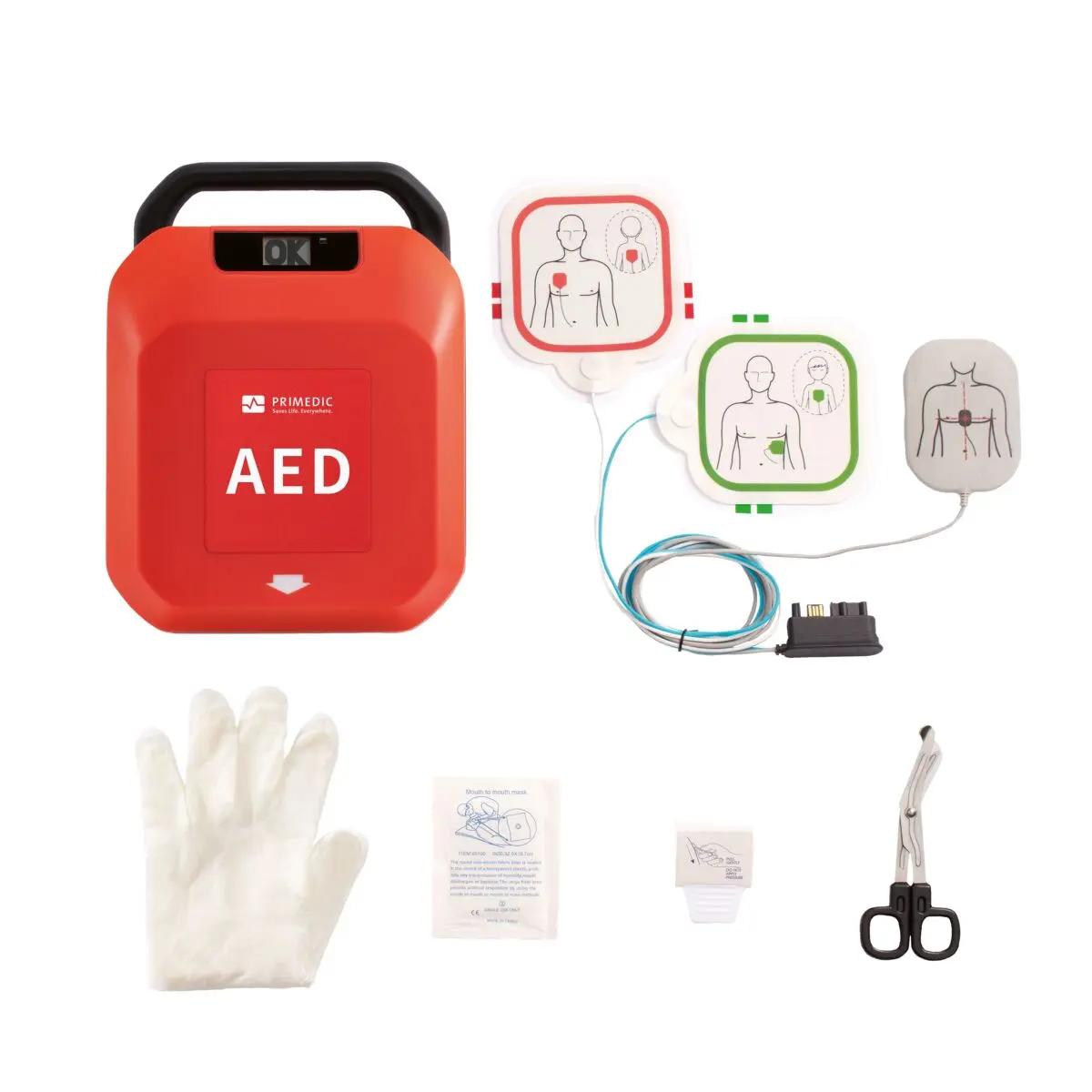 Defibrillator-Set HeartSave Y/YA in Rot-Weiß mit AED-Gerät, weißem Handschuh, schwarzen Scheren sowie Elektrode und Zubehör übersichtlich angeordnet.