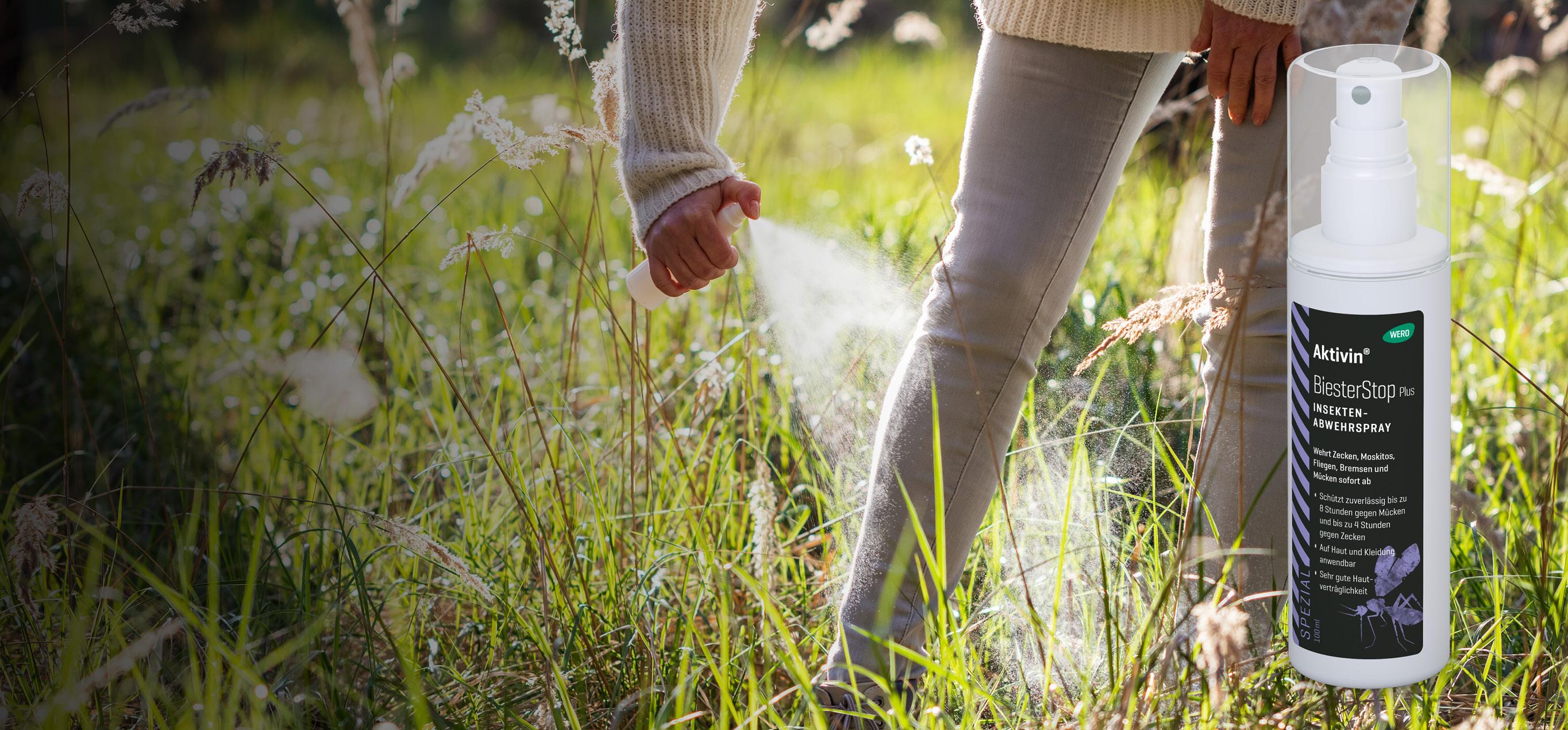 Eine Person sprüht Activin BiesterStop plus Insektenschutz mit weißem Sprühflaschenaufsatz gezielt auf hohes Gras in natürlicher Umgebung.