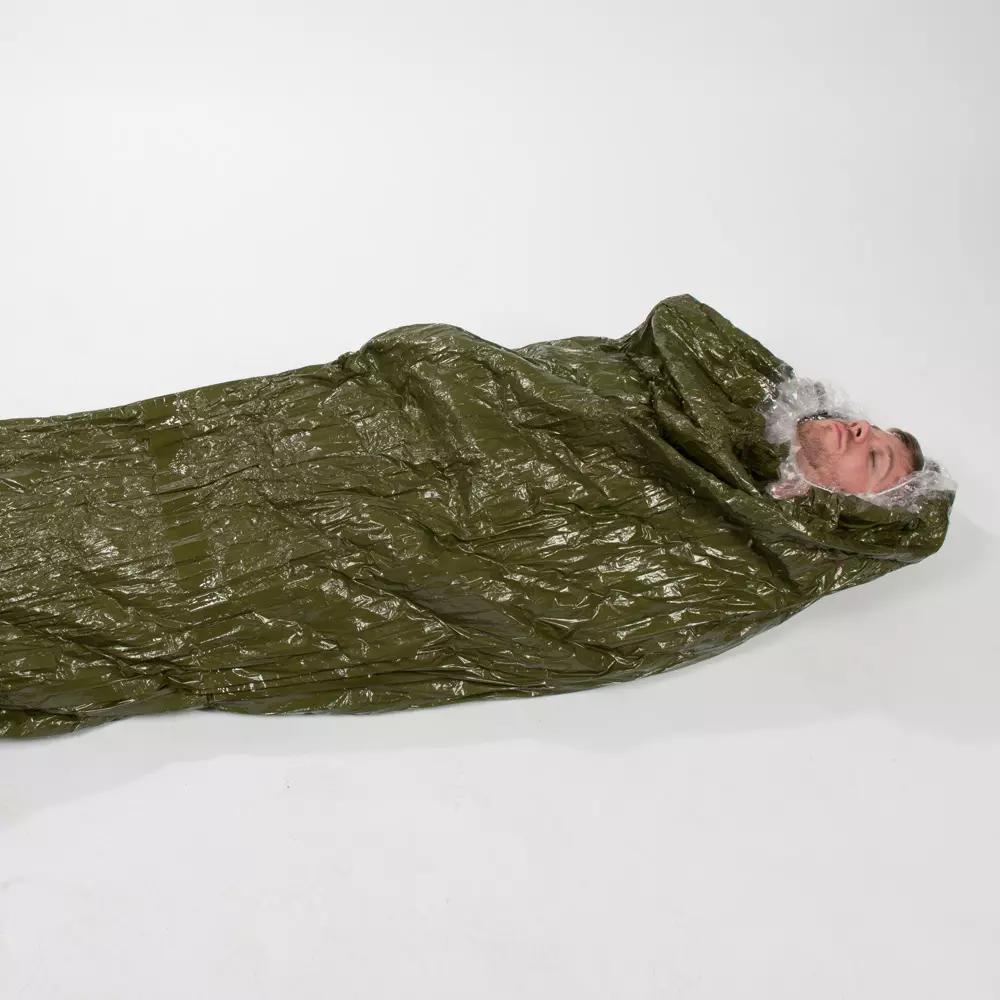Ein Mann liegt in einem Blizzard - Grün, Schlafsack mit Blizzard Reflexcell™ Technologie, der für optimale Wärmeisolierung und Schockversorgung konzipiert ist.