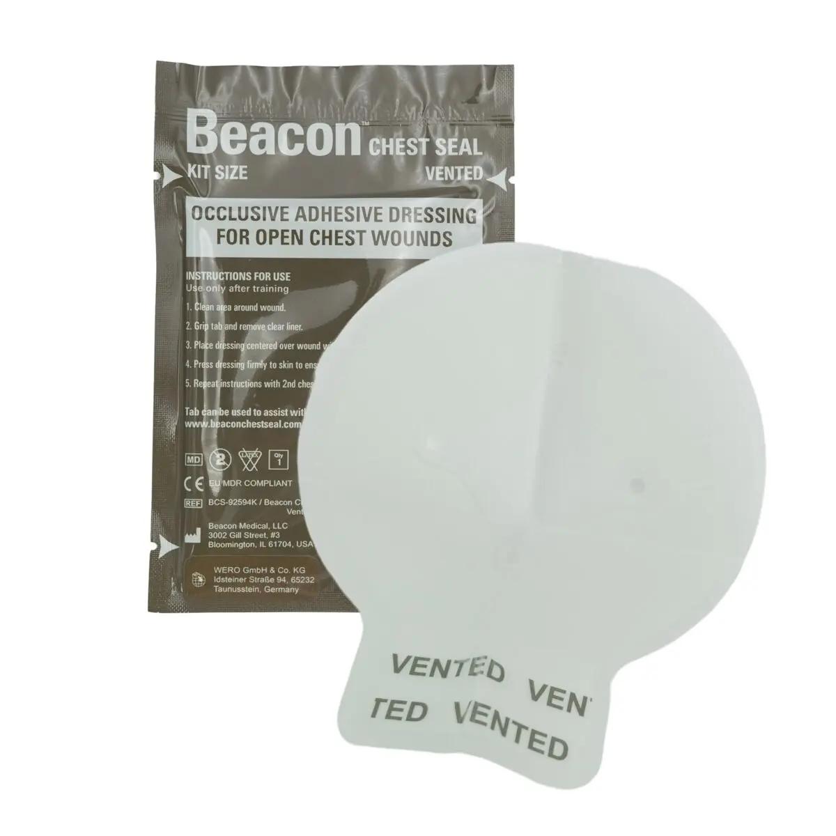 Rundes Beacon™ Chest Seal - vented, mit vier Entlüftungskanälen, liegt neben grauer, detailreicher Einzelverpackung mit Anwendungshinweisen.