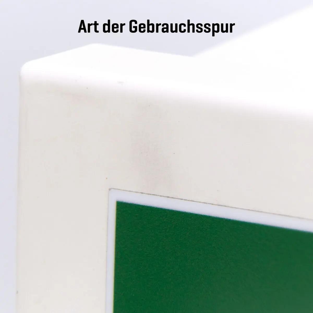 Ein AED-Wandschrank (gebraucht) - ohne Alarmfunktion mit grüner Markierung, glatter Front und sichtbaren Gebrauchsspuren auf der weißen Oberfläche.