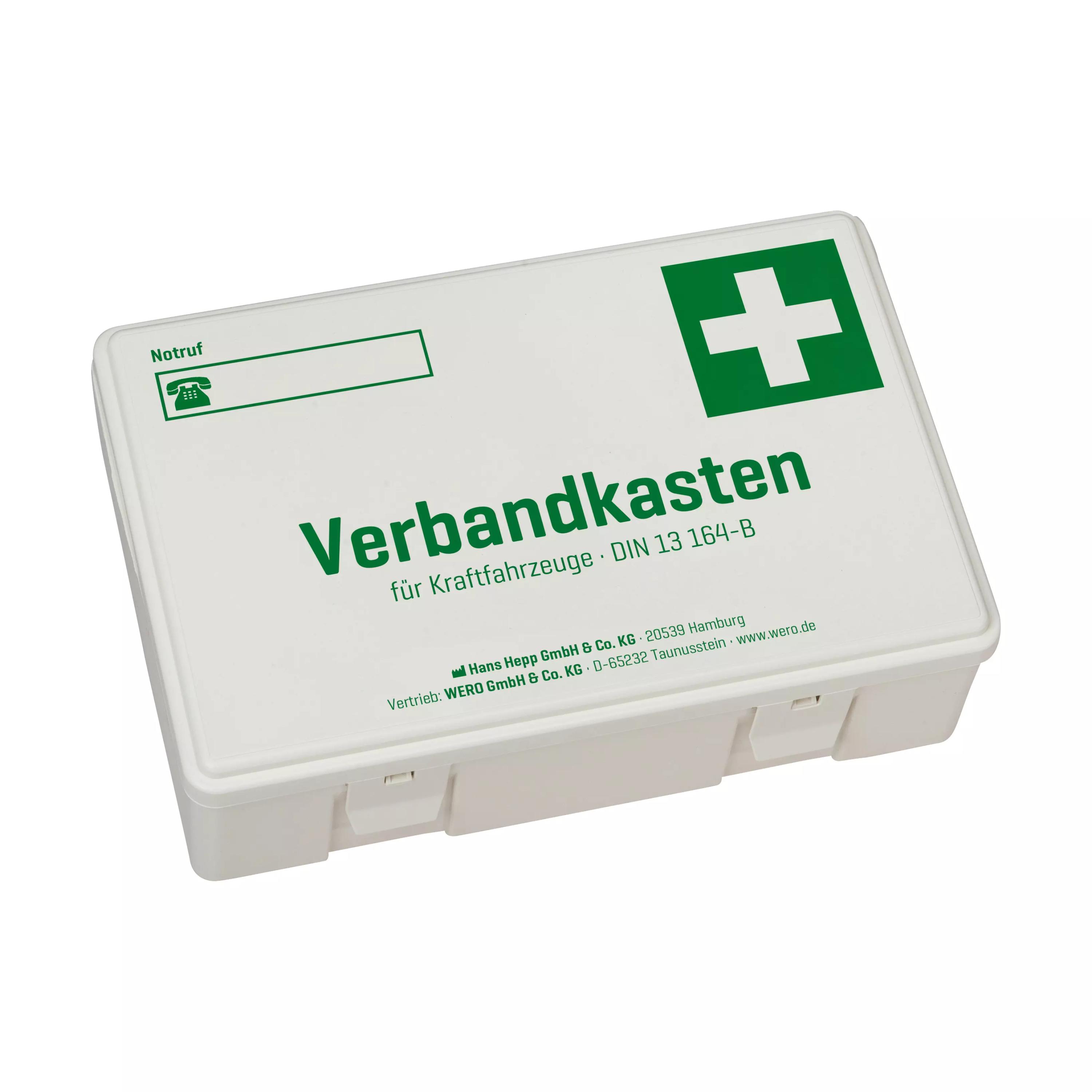 Weiße Kunststoffbox mit grünem Kreuz und der Aufschrift „KFZ-Verbandskasten DIN 13164-B“, zwei Fächern und Betriebsangaben auf dem Deckel.