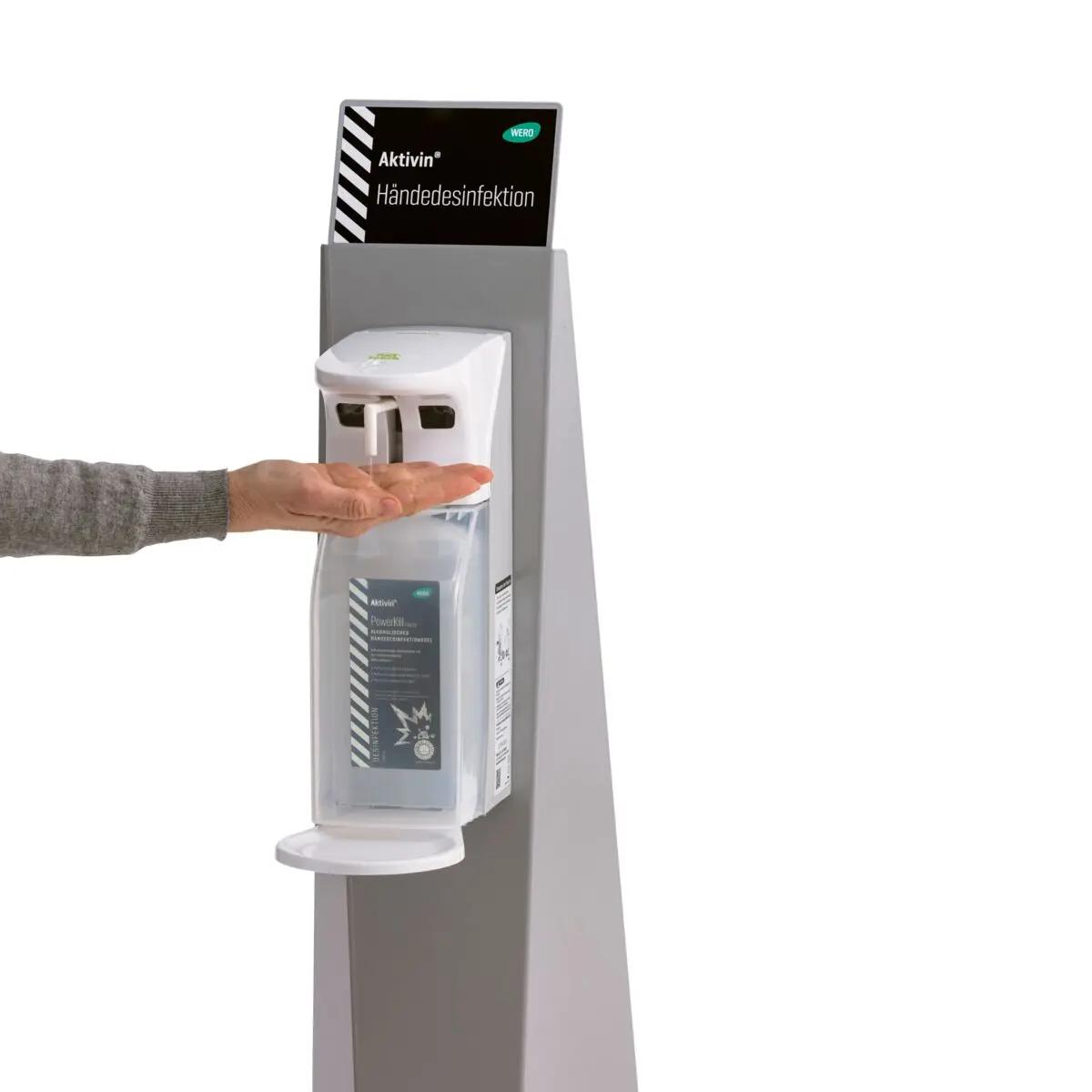Eine Hand entnimmt Desinfektionsmittel an einem Aktivin® Händedesinfektionsständer aus pulverbeschichtetem Stahlblech mit hoher Standfestigkeit.