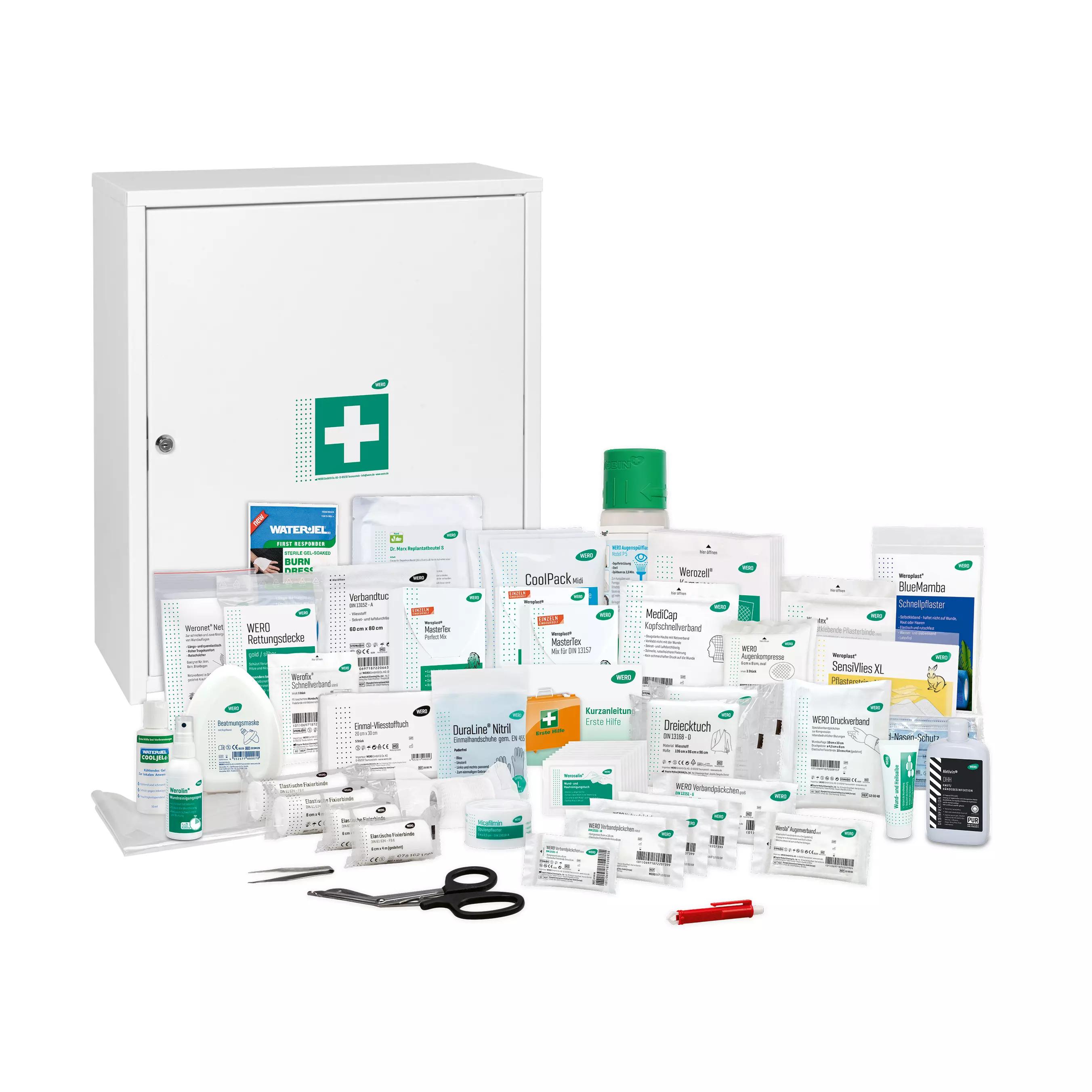 Ein WERO Verbandschrank MaxiDeep 6 / 073 mit grünem Kreuz zeigt geöffnete Tür, sortierte Bandagen, Schere und Fläschchen vor dem Schrank.