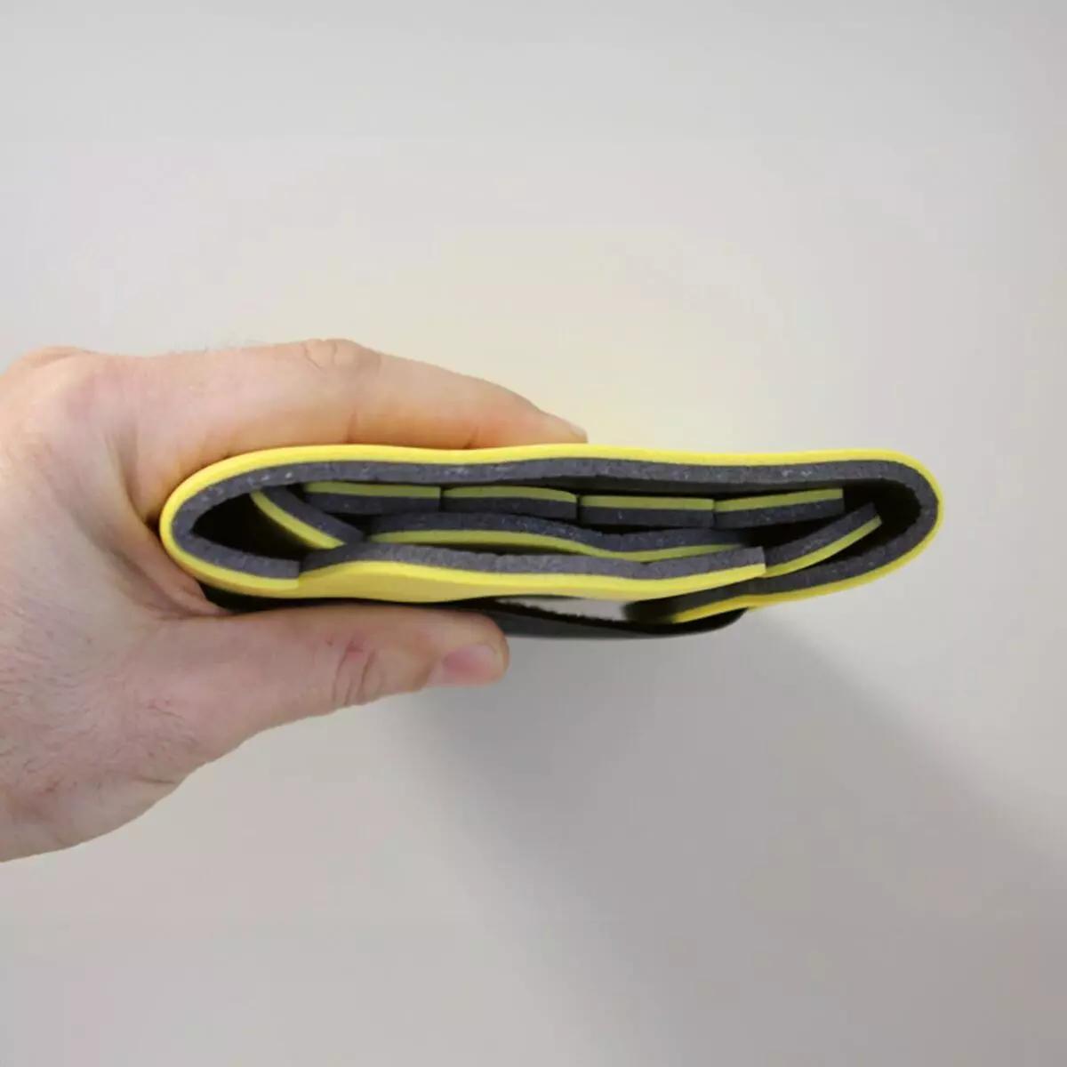 Alt-Text: Eine Hand hält einen gefalteten Immobilisationskragen Necklite™ - Gelb mit PU-Schaum-Ummantelung und flexiblem Aluminiumkern.