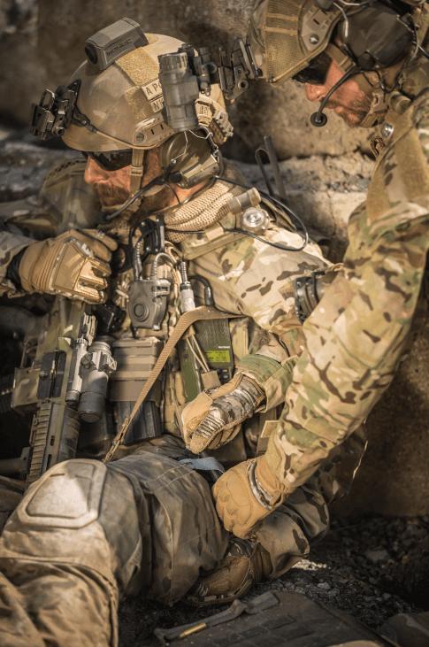 Zwei Soldaten in Tarnuniform und Schutzwesten stehen sich mit angespannten Gesten bewaffnet in felsigem Gelände gegenüber.