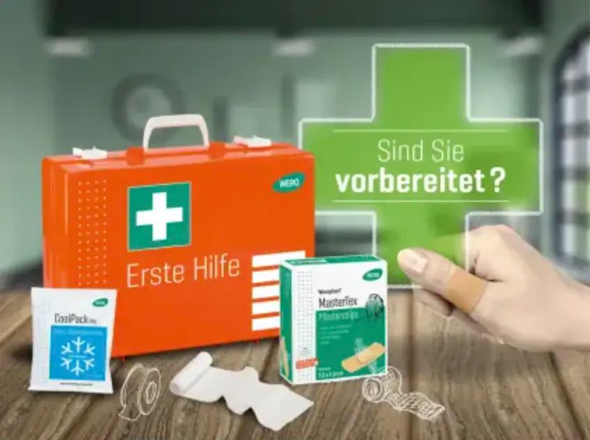Oranger Erste-Hilfe-Kasten mit grünem Kreuz, daneben Masterflex Pflasterstrips, Klebeband und Hand mit Fingerverband