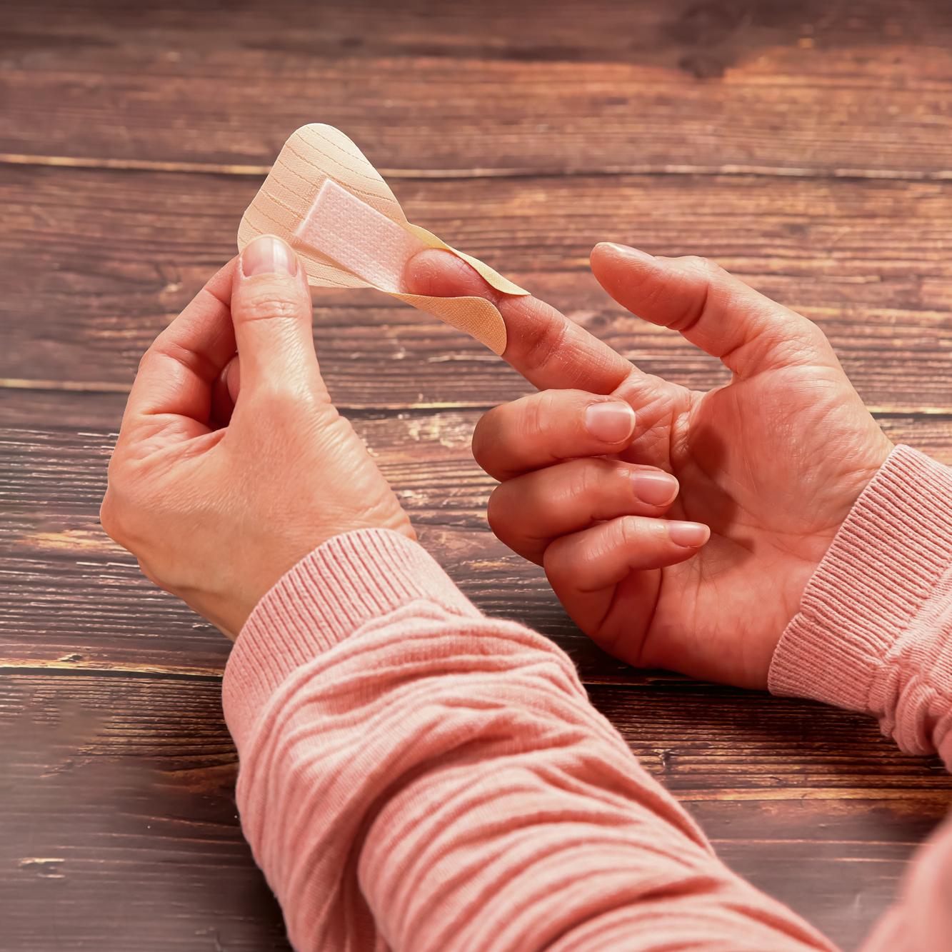 Eine Person befestigt ein Fingerkuppenpflaster Weroplast® MasterTex mit hohem Tragekomfort, textiler Oberfläche und hoher Anpassungsfähigkeit am Finger.