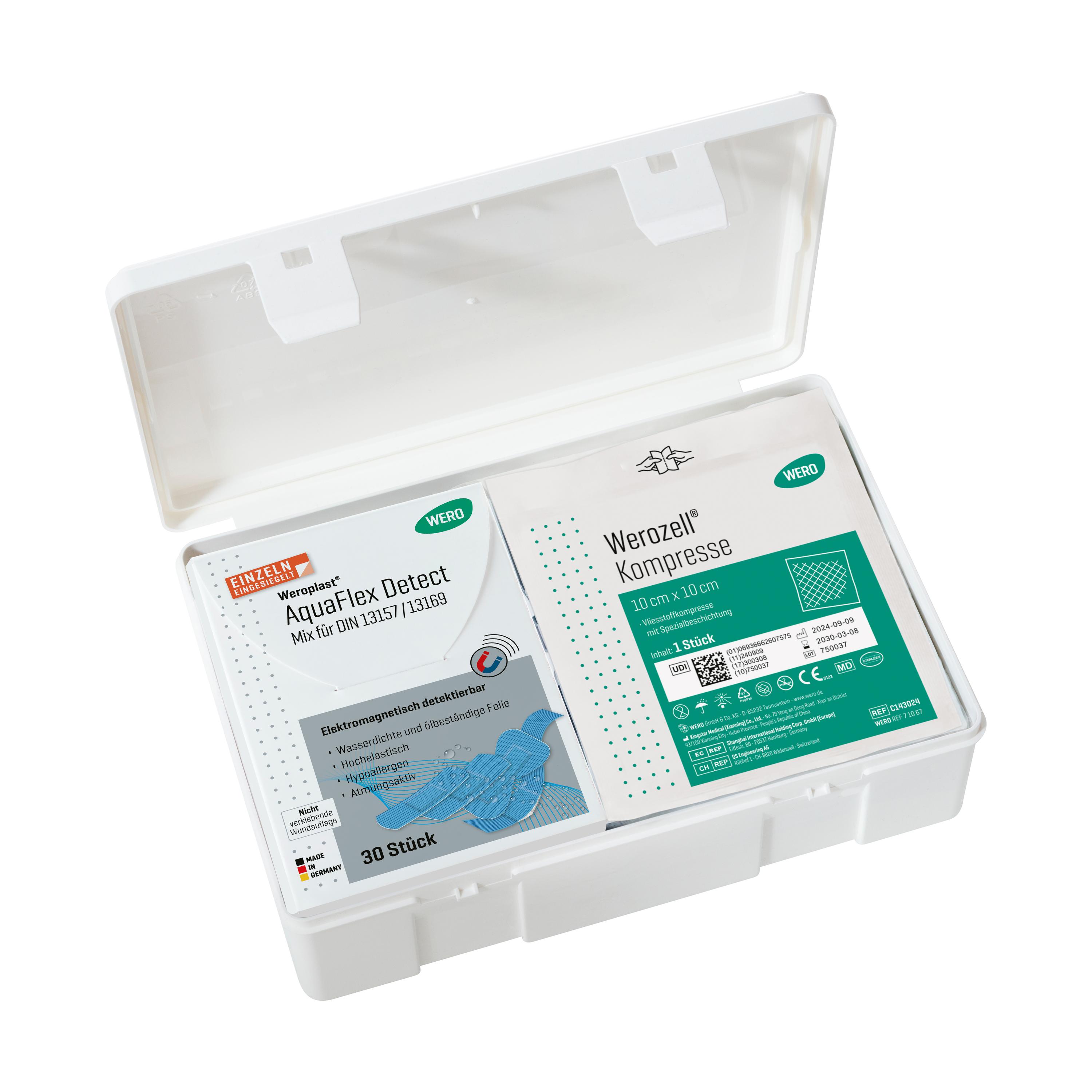 Ein offener Verbandkasten DIN 13157-C, detektierbar, zeigt zwei medizinische Päckchen mit detektierbaren Pflastern und Kompressen.