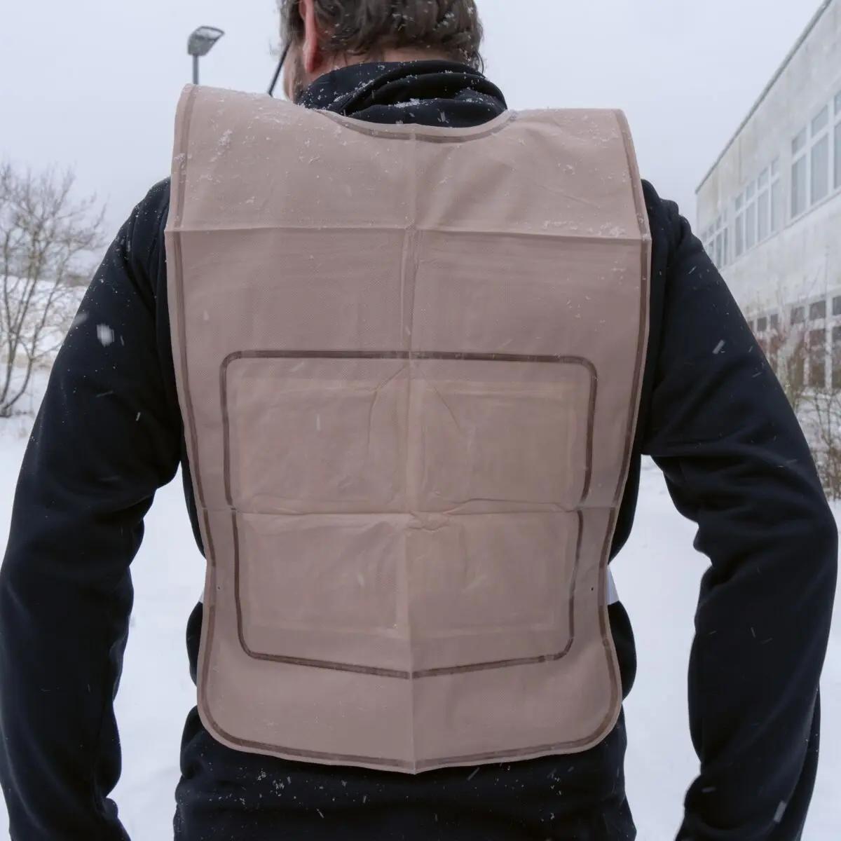 Eine Person trägt die beige Ready-Heat™ - Weste mit integrierten Wärmeelementen aus synthetischer, wasserfester Faser in verschneiter Landschaft.